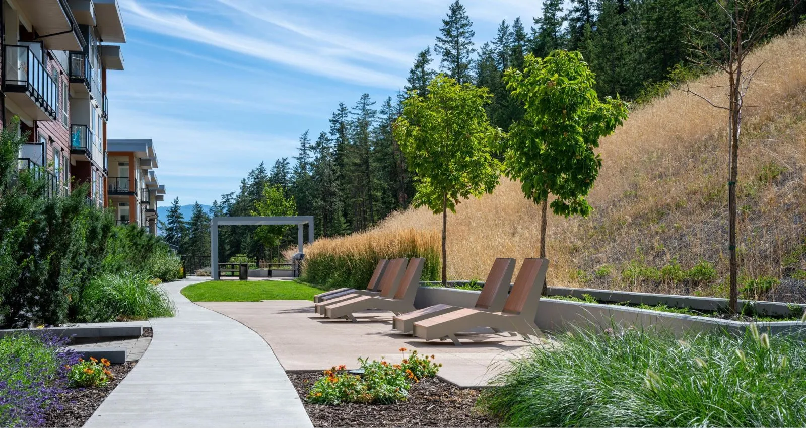 These JEM Chaise Loungers provide a relaxing outdoor seating option. The modern design complements the surrounding landscape at Knox Village in Kelowna, British Columbia.