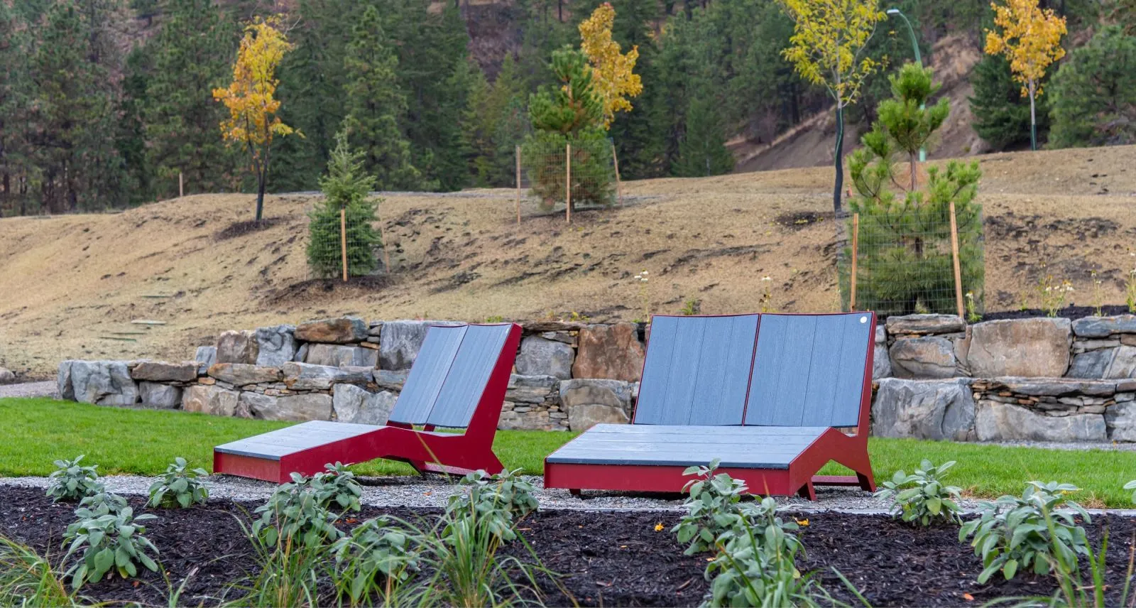 These double chaise loungers offer a relaxing spot in a landscaped park. The recycled plastic lumber seats and brightly colored frames provide comfortable and stylish seating.