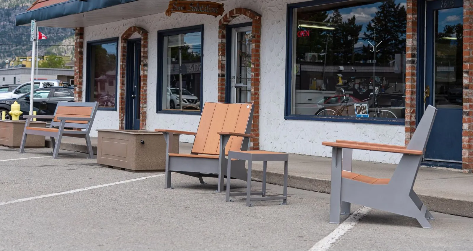 Outdoor seating area featuring lounge chairs, a side table, a bench, and planters. The furniture is made with recycled plastic lumber and powder-coated metal frames, creating a comfortable and inviting space.