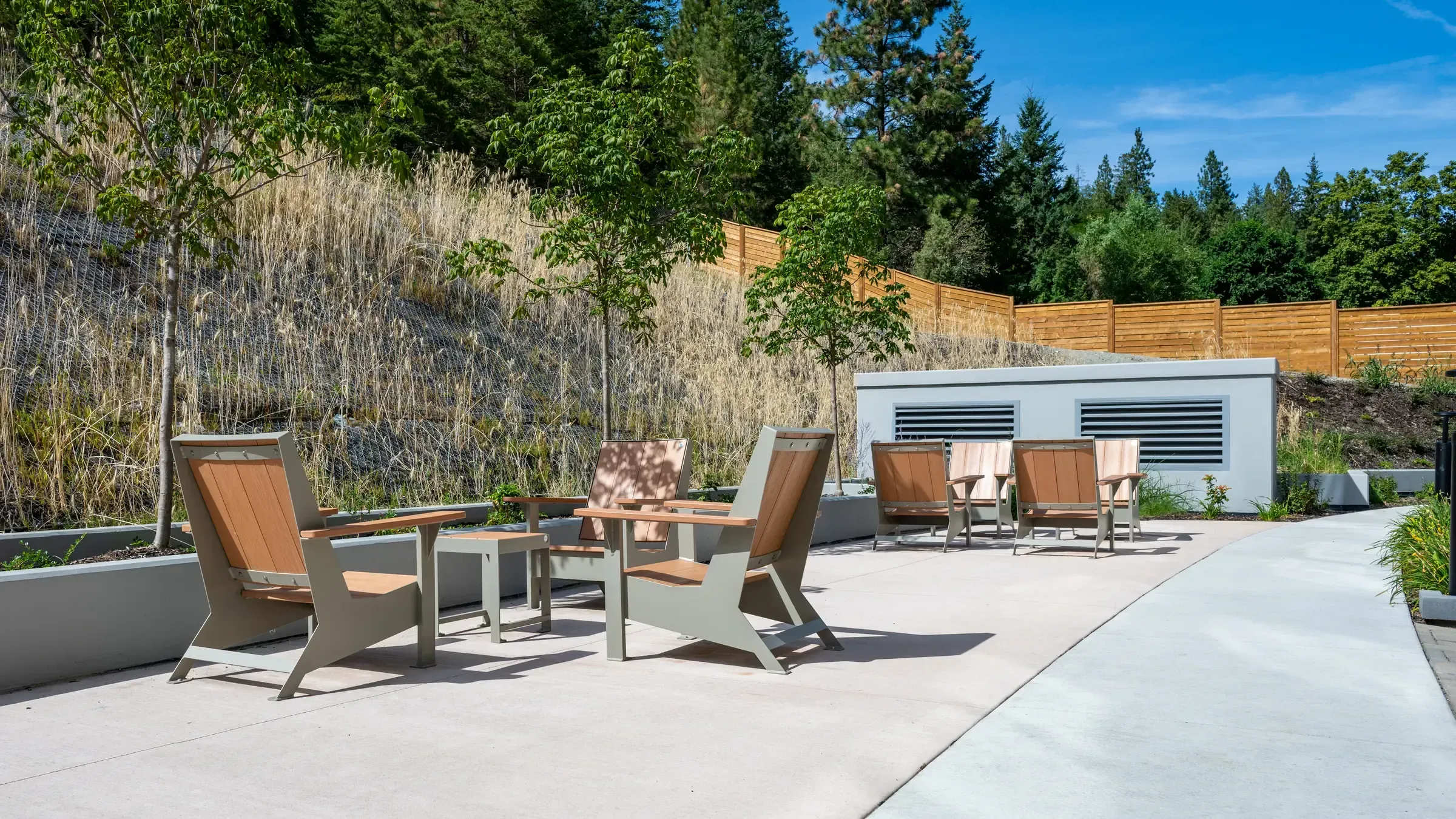 Outdoor lounge area featuring Jem Lounge Chairs and a Side Table. The furniture is arranged on a concrete patio with a hillside backdrop.