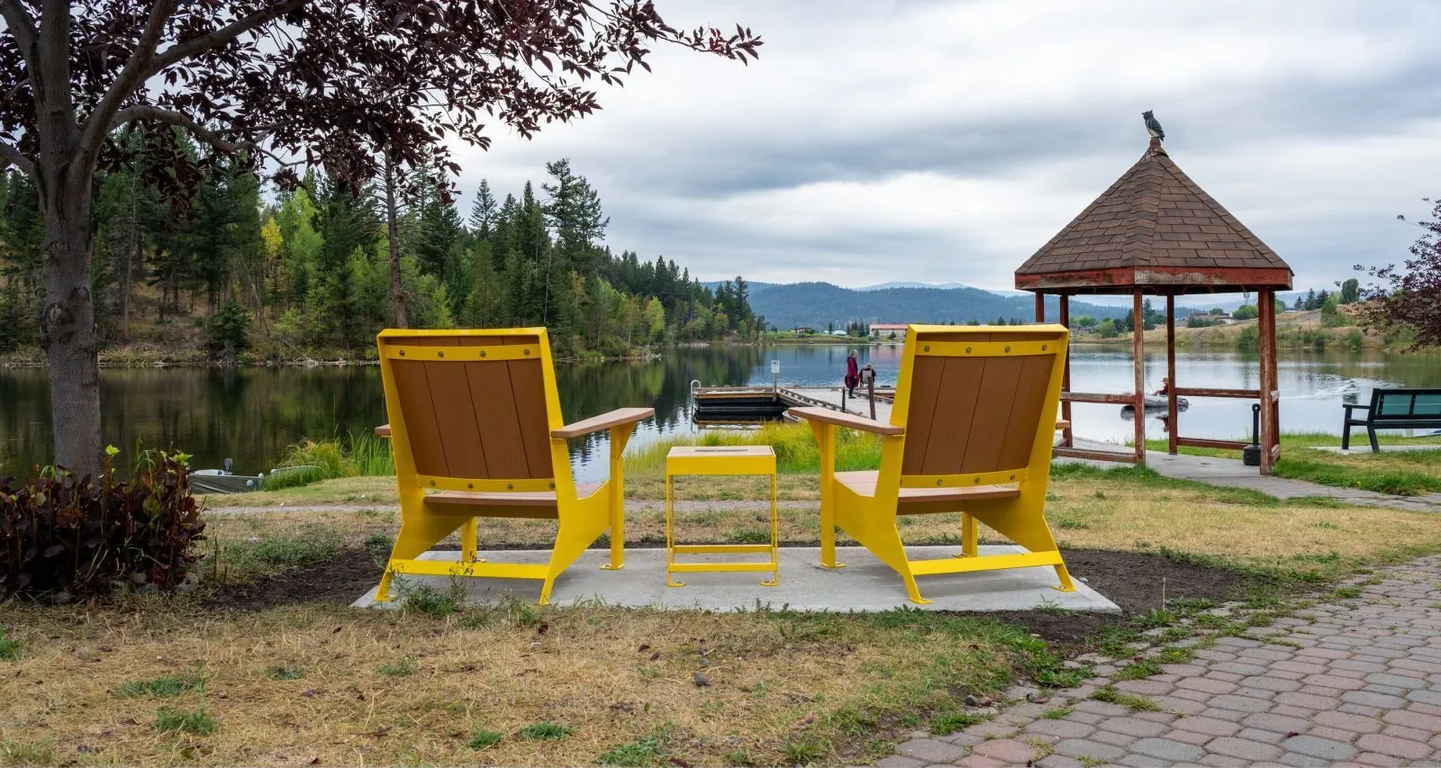 Enjoy the view from these oversized Adirondack chairs and side table. The bright yellow frames and brown recycled plastic lumber add a pop of color to this lakeside setting.