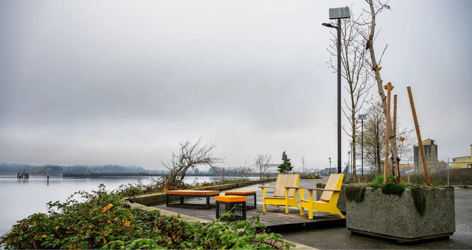 Outdoor lounge area featuring JEM Lounge Chairs and Side Tables. The setting overlooks the water on an overcast day.