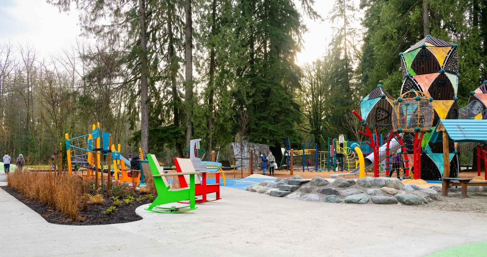 Colorful rocking chairs provide seating at a playground. The chairs feature recycled plastic lumber and powder-coated metal frames.
