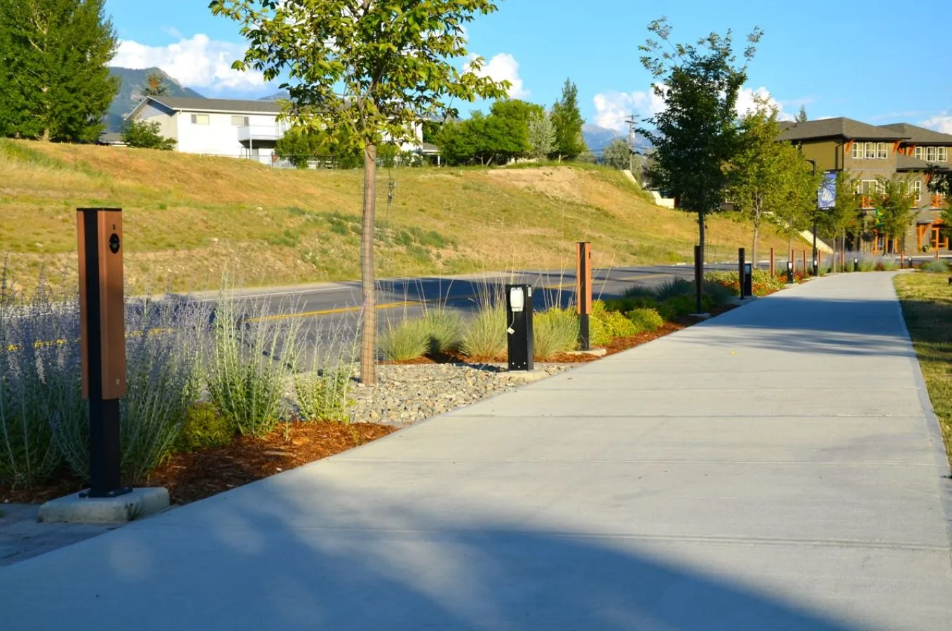These LED bollards provide pathway lighting along a landscaped walkway. The bollards feature a wood-look panel and a black powder-coated frame.