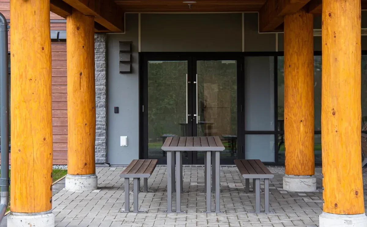 Larson picnic table with attached benches provides outdoor seating. The table features recycled plastic lumber and a powder-coated metal frame.