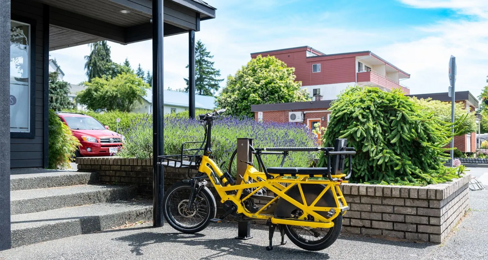 A Modena 2 Space Bike Rack provides secure parking in a landscaped area. The bike rack features a durable powder-coated finish.