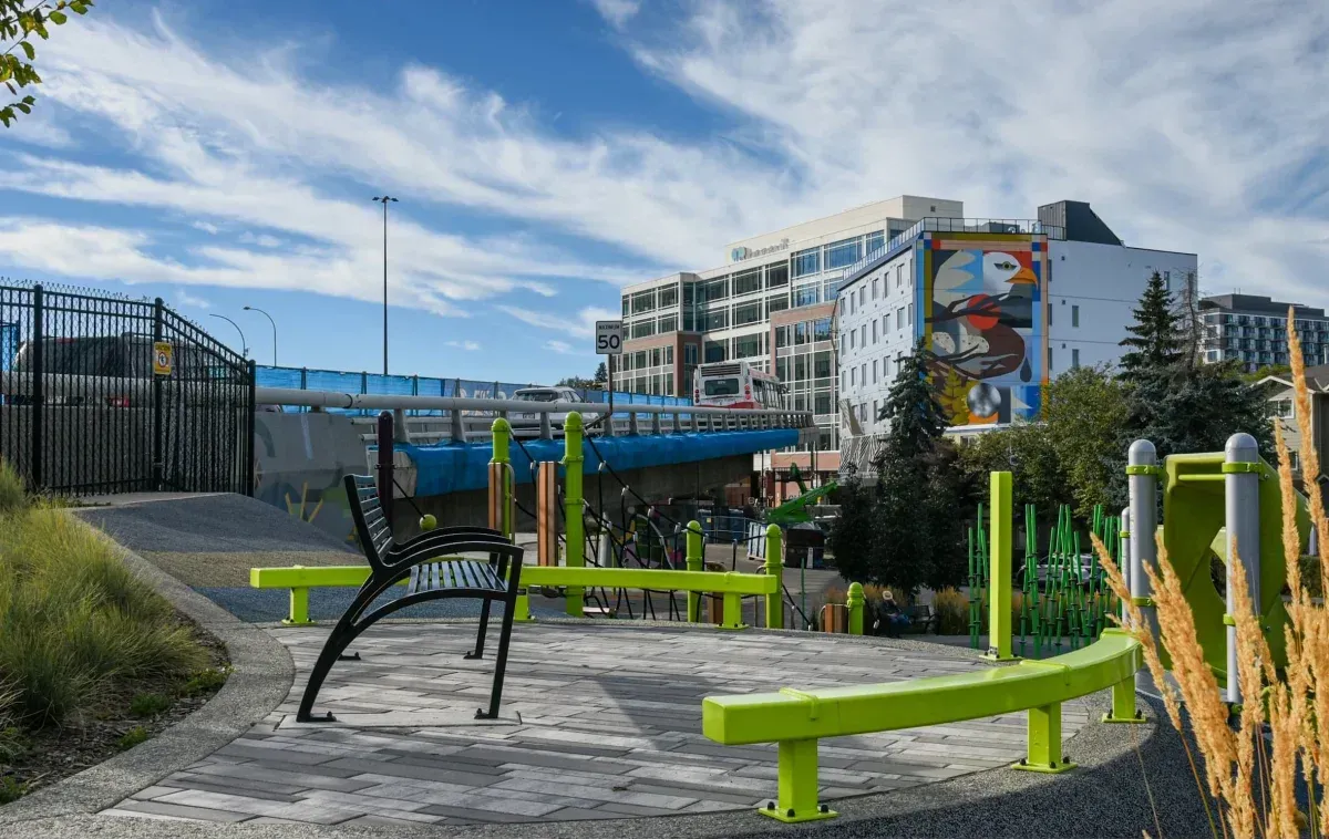 Modena Aluminum Bench provides seating at Flyover Park in Calgary, Alberta. The bench features a black frame and complements the park's modern design.