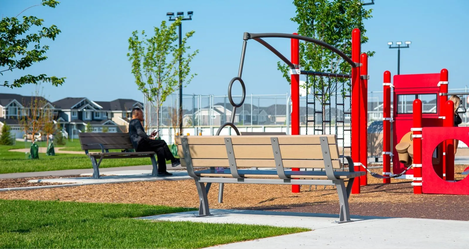 Durable benches provide seating at Horizon Station Park in Regina, Saskatchewan. The site furniture complements the playground and green space.
