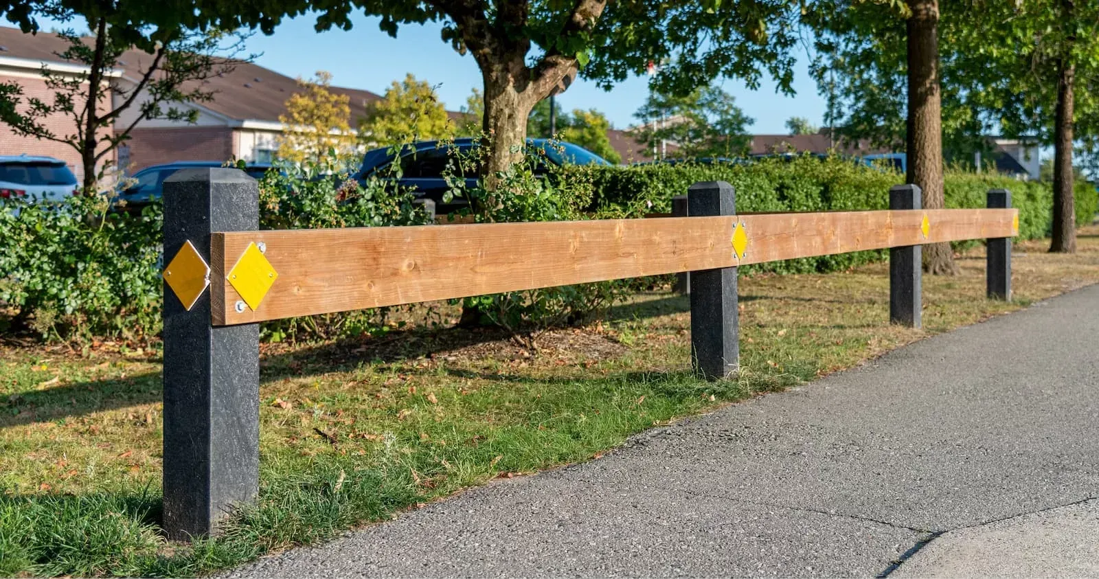 Perma-Post site furniture elements create a barrier along a pathway. The posts feature a wood-look horizontal beam and yellow reflectors.