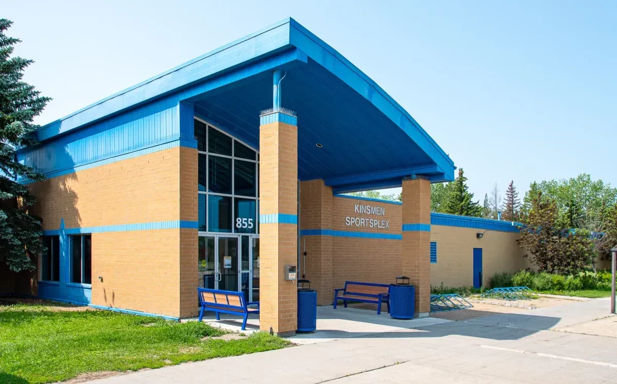 Benches and waste receptacles are placed outside the Kinsmen Sportplex in Moose Jaw, Saskatchewan. The benches feature recycled plastic lumber seats and blue powder-coated frames.