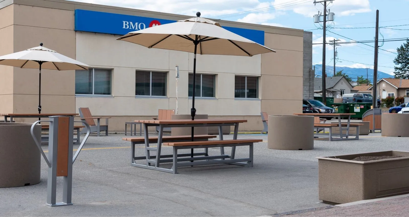 Outdoor seating area with Rutherford picnic tables and planters provides a comfortable space for bank customers. The site furniture features recycled plastic lumber and powder-coated metal frames.
