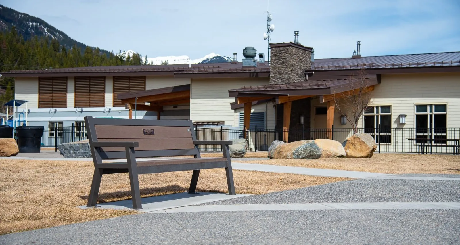 The Rutherford bench provides comfortable seating in a park setting. The bench features recycled plastic lumber and a powder-coated metal frame.