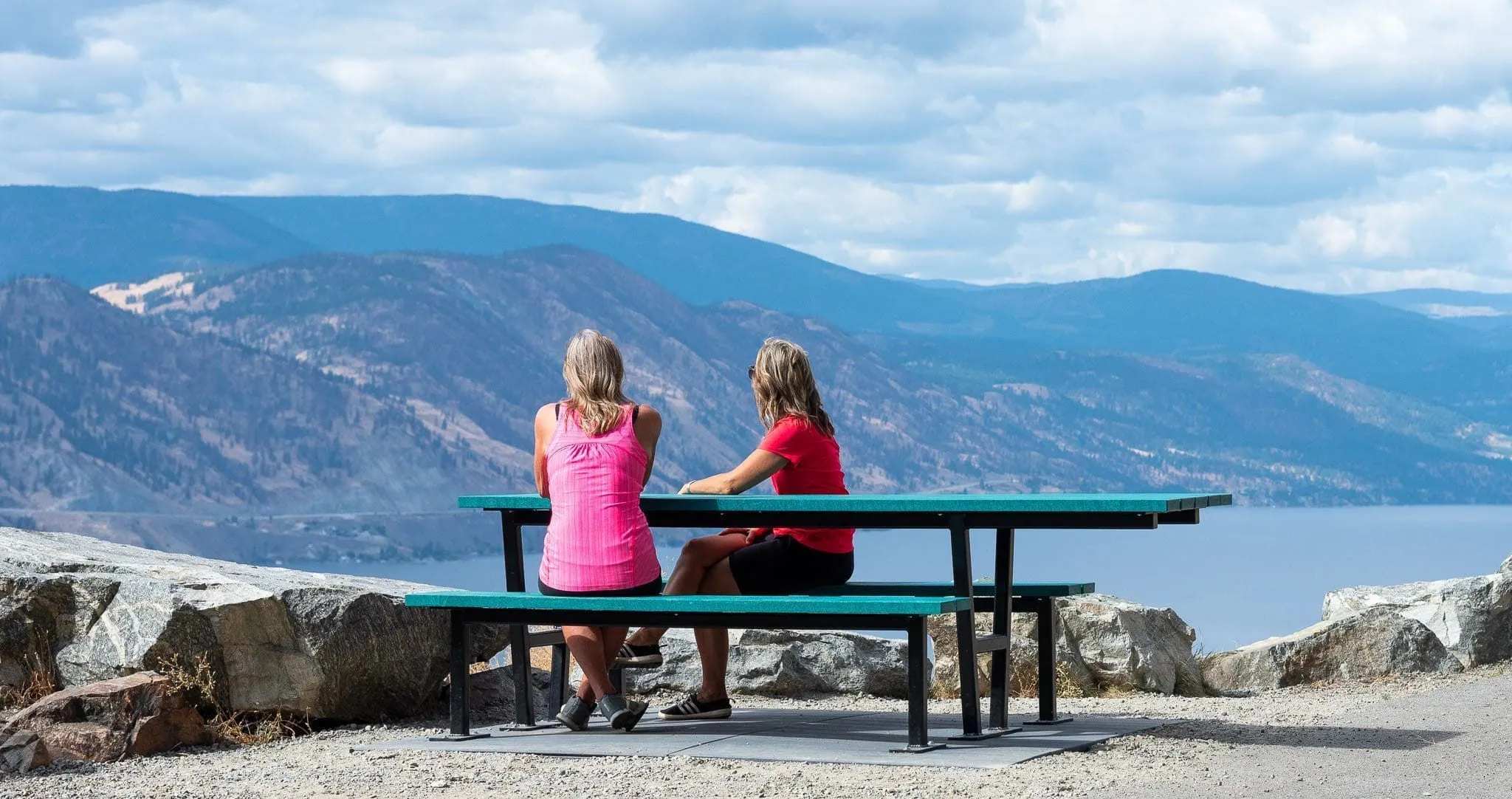 Wheelchair-accessible picnic table offers a scenic view of the surrounding mountains and lake. The table features a durable recycled plastic lumber top and a sturdy metal frame.
