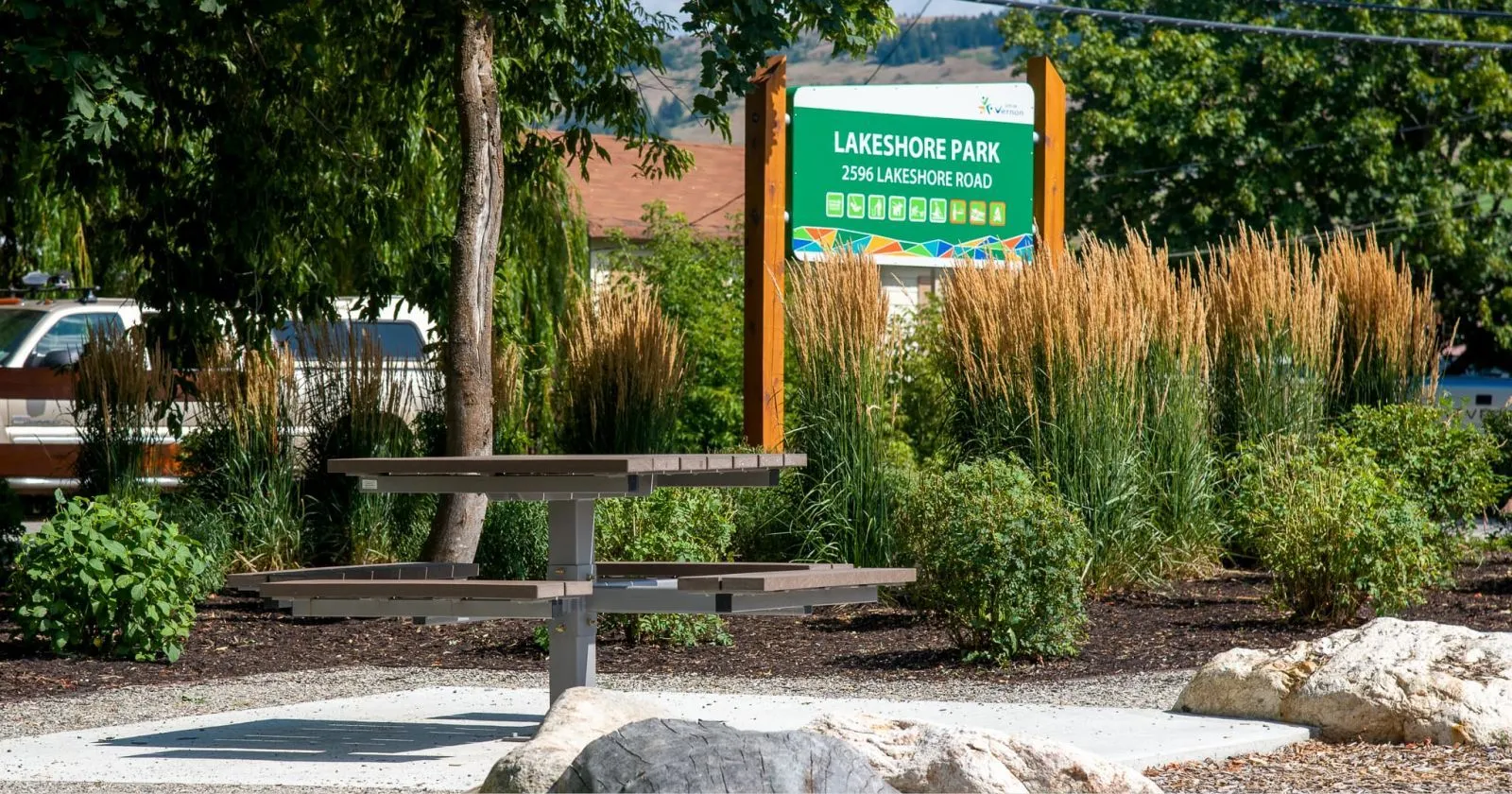 A single pedestal picnic table provides a place to rest at Lakeshore Park in Vernon, British Columbia. The table features recycled plastic lumber and a powder-coated metal frame.