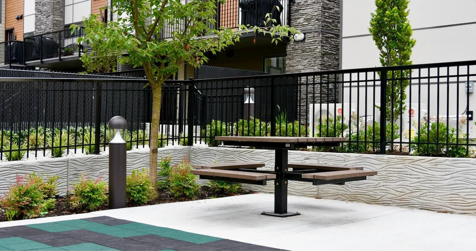 A single pedestal picnic table provides an outdoor gathering spot. The table features recycled plastic lumber and a black powder-coated frame.