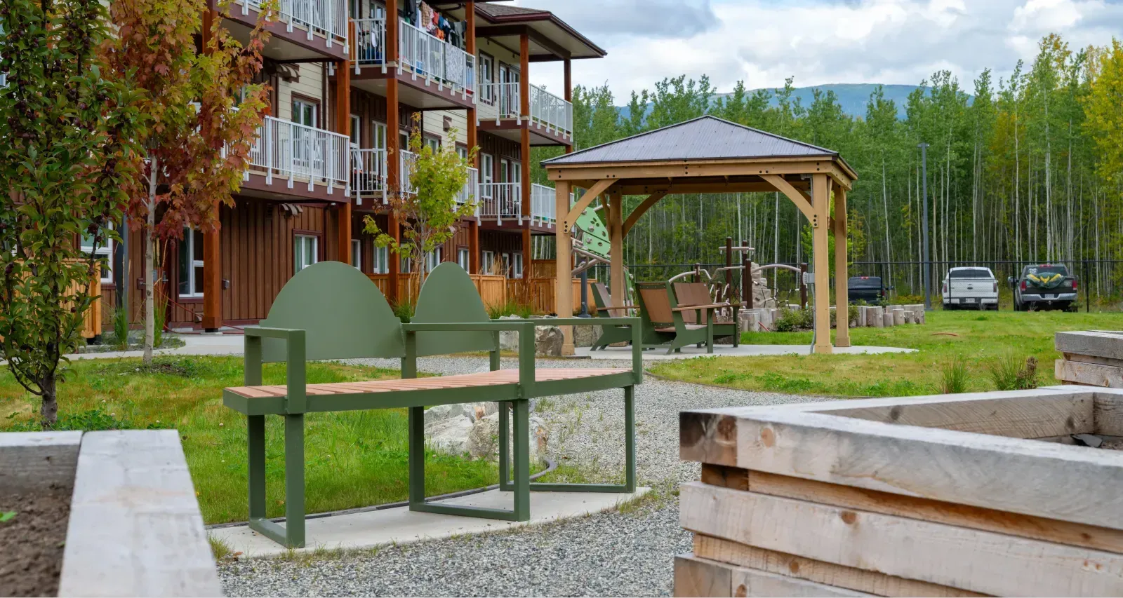 Skyline Curved Bench with a custom backrest adds a touch of modern design to this outdoor space. The bench features a green powder-coated frame and wood-look recycled plastic lumber.