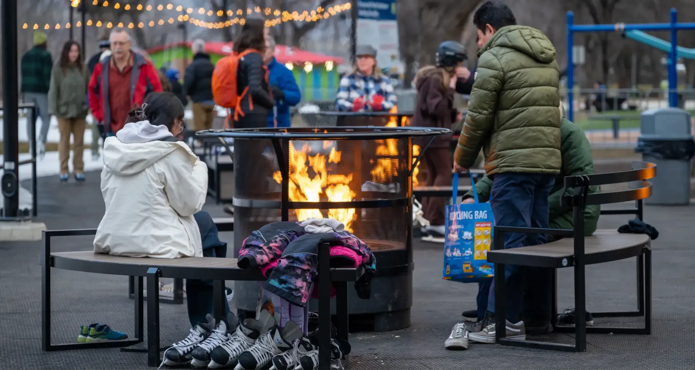 Curved benches surround a fire pit at the Riverside Skating Loop in Kamloops, British Columbia. The benches provide seating for skaters and visitors to warm up by the fire.