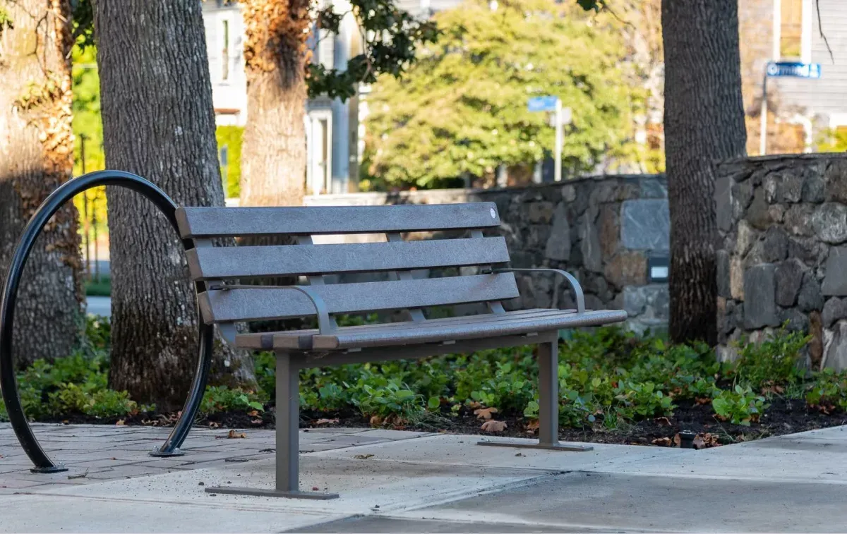 Standard bench with armrests and a loop bike rack create a welcoming rest stop. The bench features recycled plastic lumber and a powder-coated metal frame.
