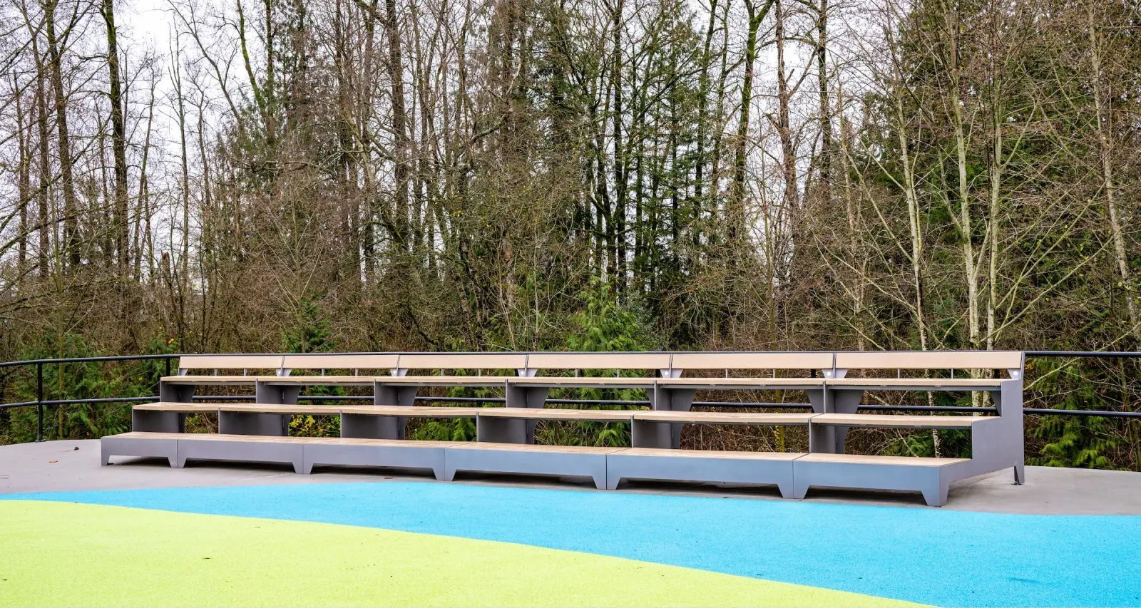 Strataview Step Bench provides tiered seating in an outdoor setting. The bench features recycled plastic lumber and a powder-coated metal frame.