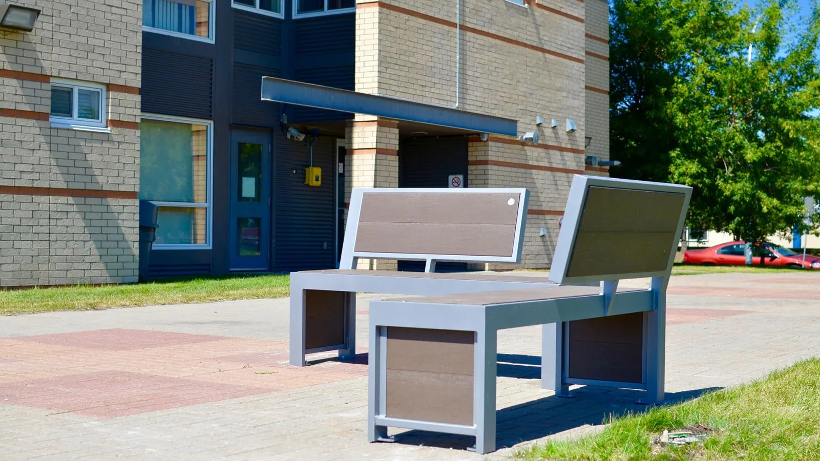 Urban Form benches provide comfortable seating outside a building at King's University in Edmonton, Alberta. The benches feature recycled plastic lumber and powder-coated metal frames.