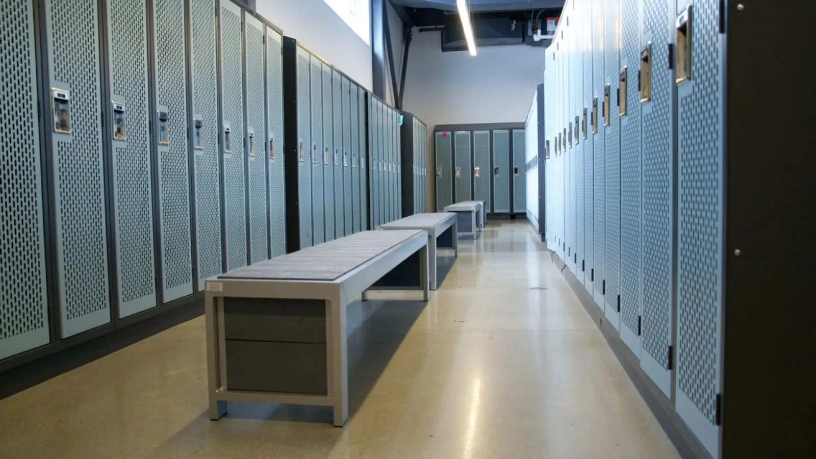 Straight benches provide seating in a change room setting. The benches feature a metal frame and a recycled plastic lumber seat.