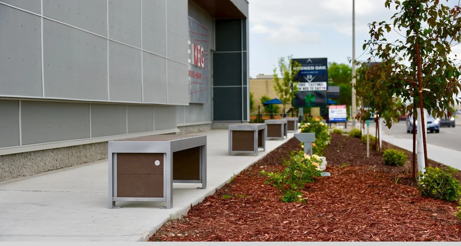 Contemporary benches provide seating outside a commercial building. The benches feature recycled plastic lumber and powder-coated metal frames.