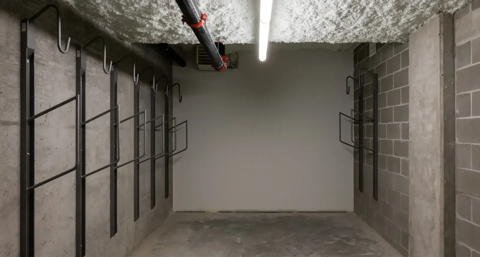 Urban Space bike racks provide secure bicycle parking in an indoor setting. The racks are wall-mounted in a concrete parking garage.