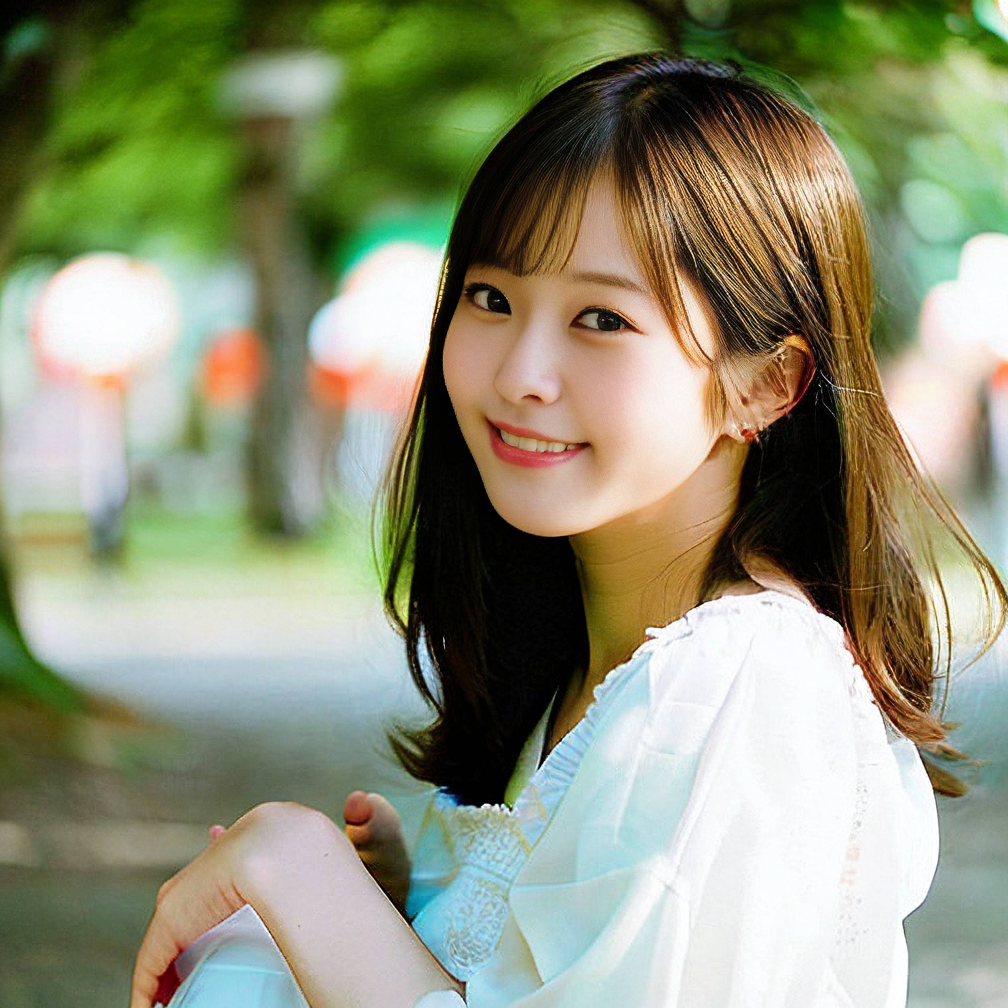 a beautiful young woman sitting on a park bench 