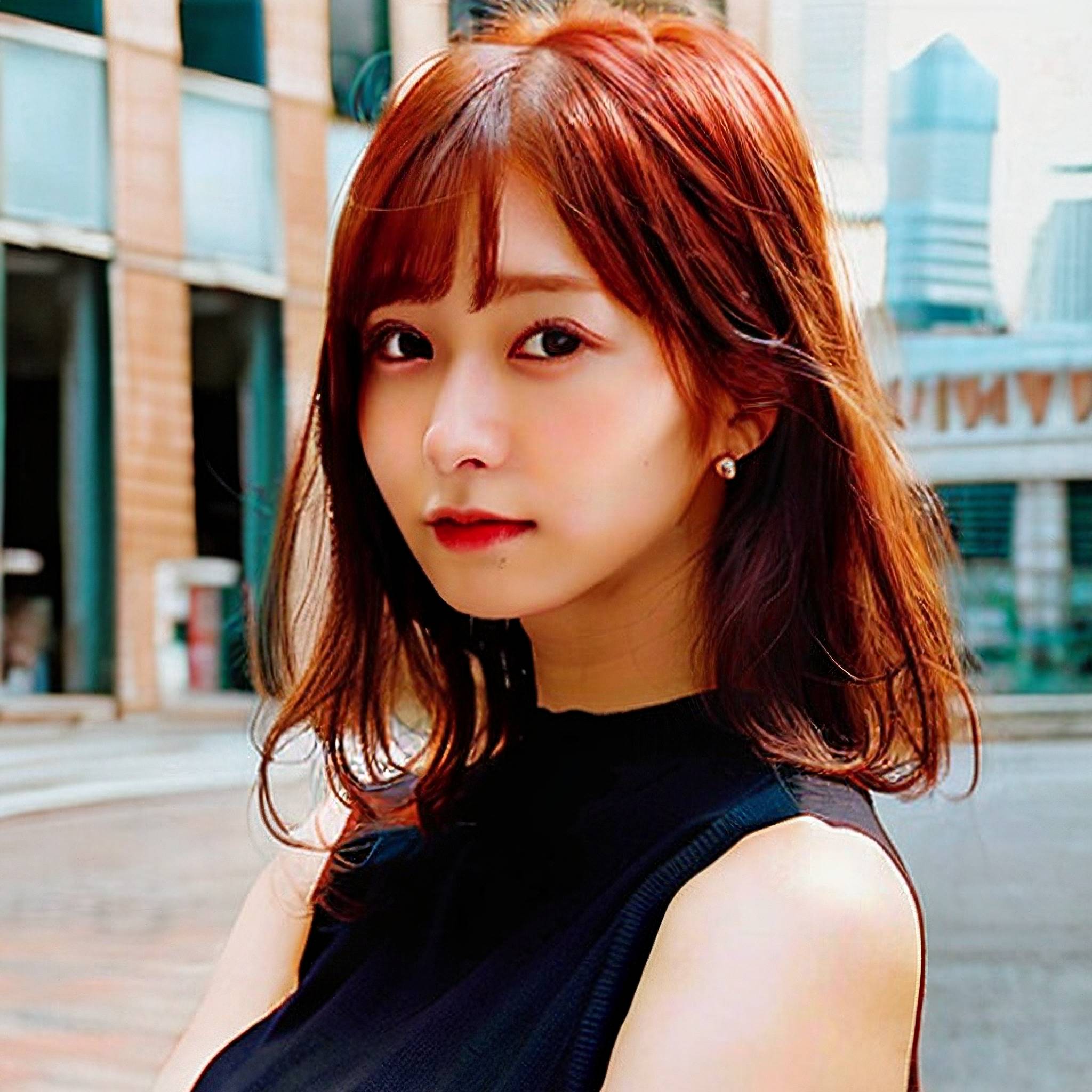 a woman with long hair standing in front of a building 