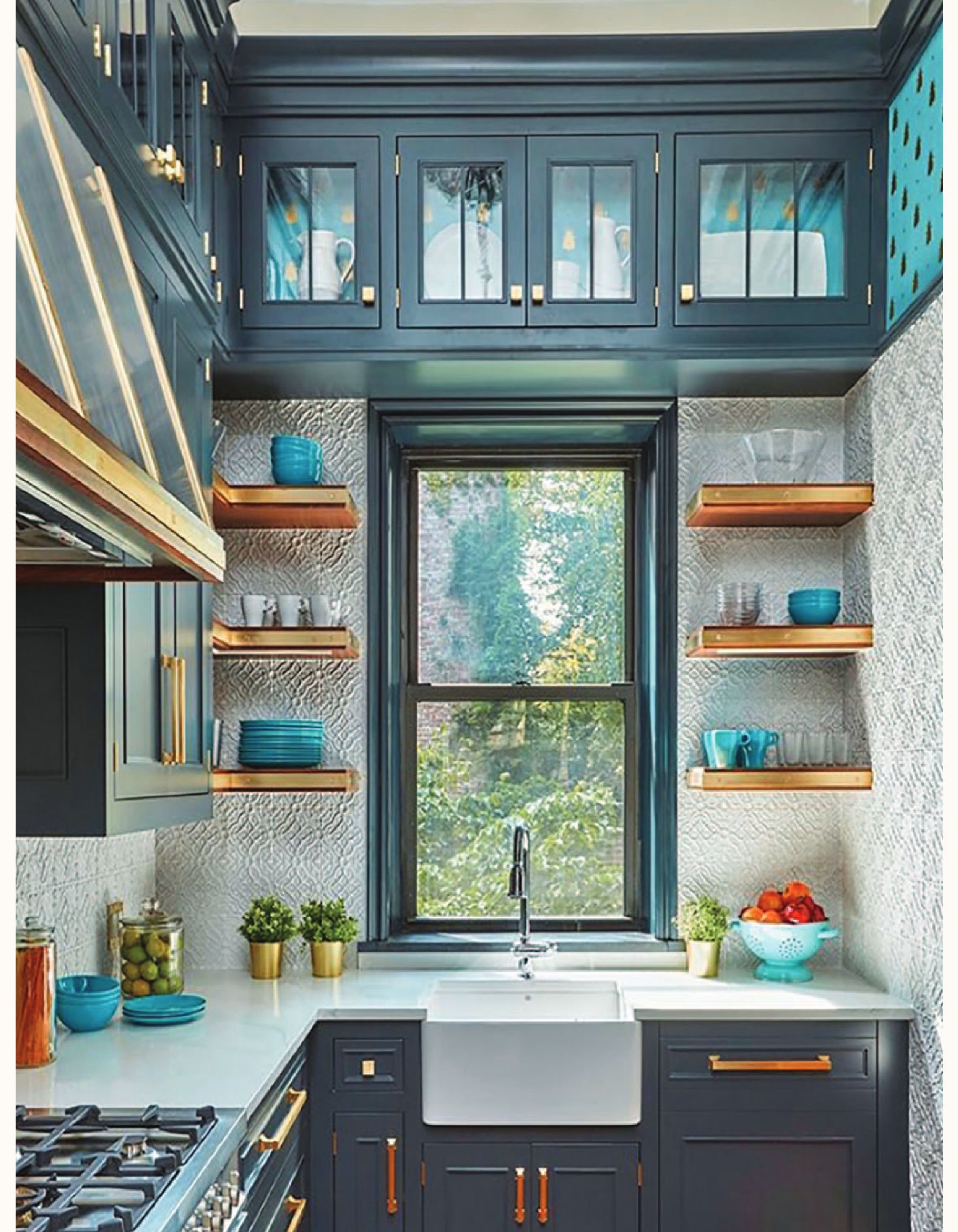 A kitchen with dark blue cabinets, open wooden shelves, and a farmhouse sink beneath a window.
