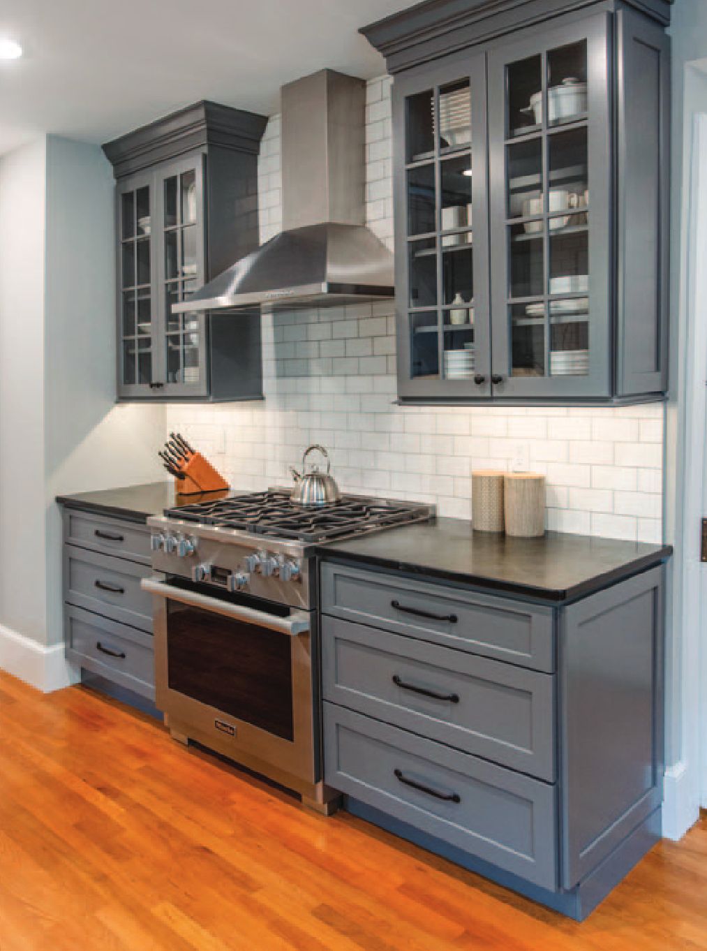 Kitchen with dark grey cabinets and white tiled backsplash.