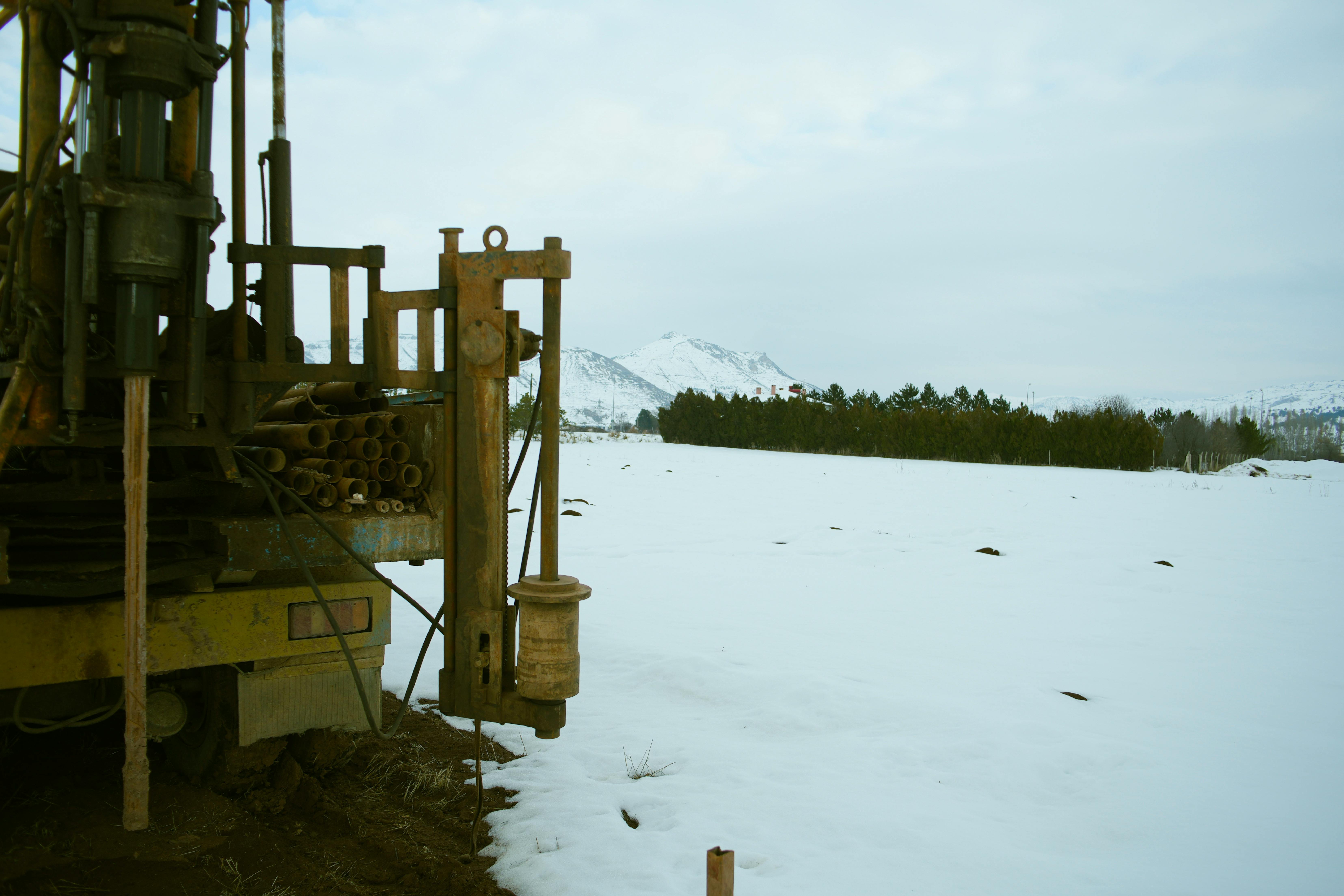 A photorealistic image showcasing a group of construction tools and a hard hat covered in snow, placed on a wooden surface at a construction site duri