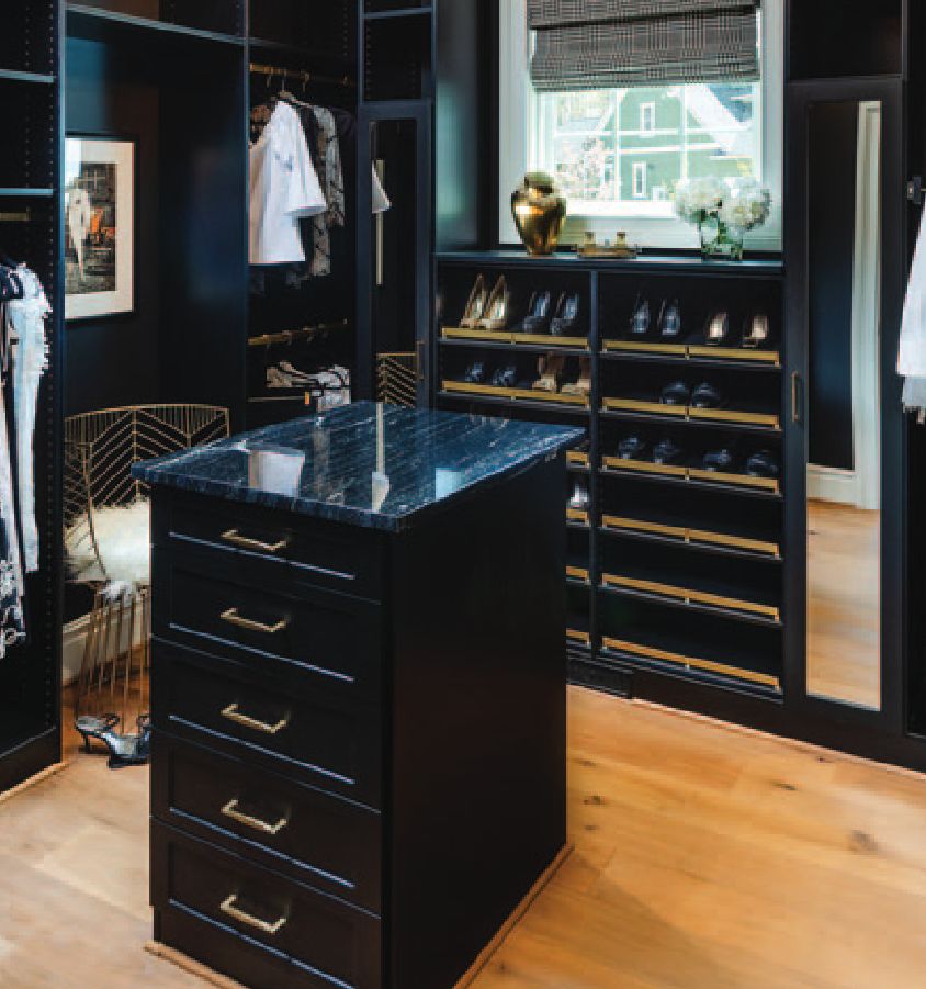 A modern closet with a central island and dark wood cabinetry.
