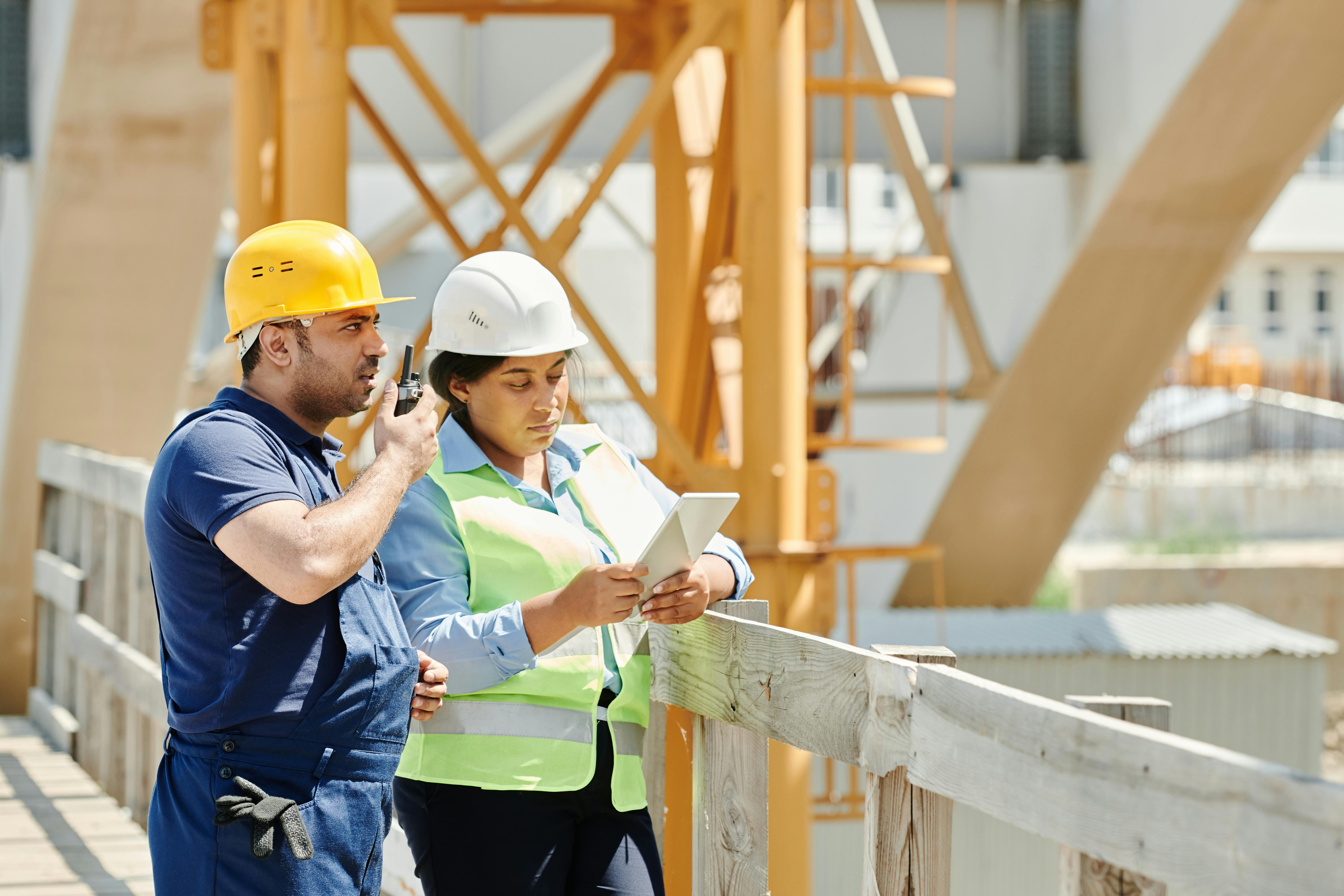 A smiling contractor in work attire, without showing the face, discussing plans with a homeowner in front of a home undergoing renovation. The scene i