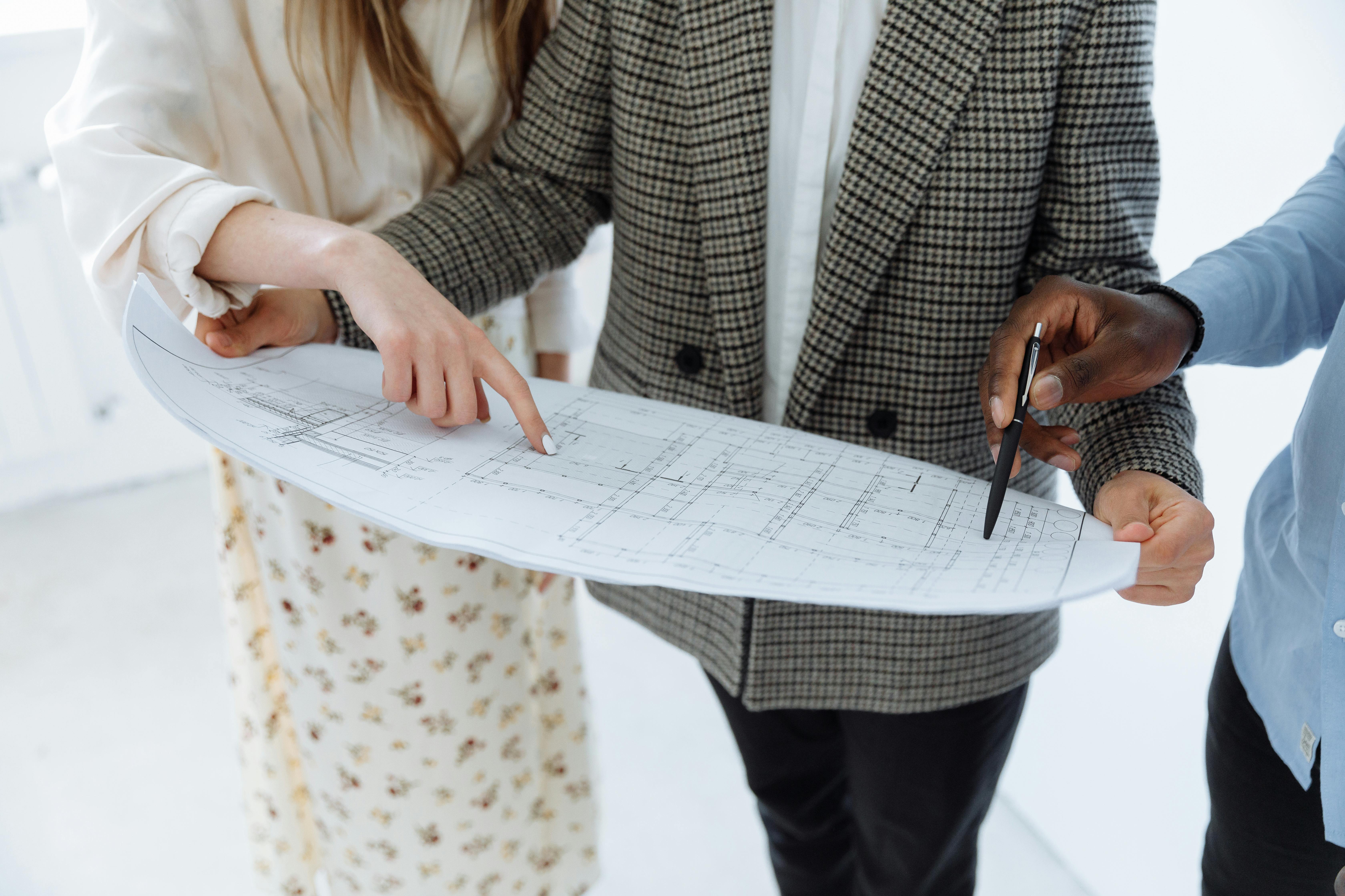 A professional, friendly contractor discussing plans with a homeowner in a well-lit, modern kitchen. The contractor is pointing to a document that app