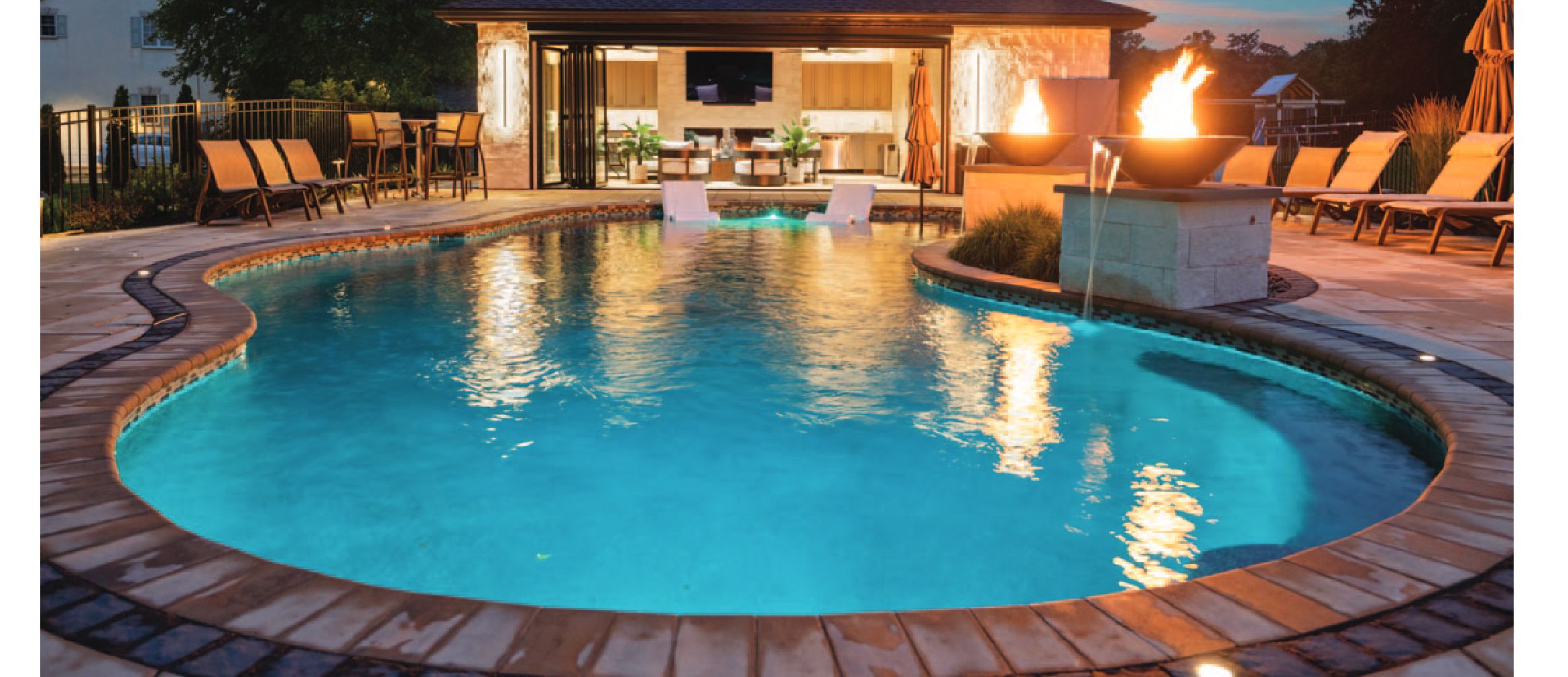 A beautiful backyard pool with patio furniture and a pool house at sunset.