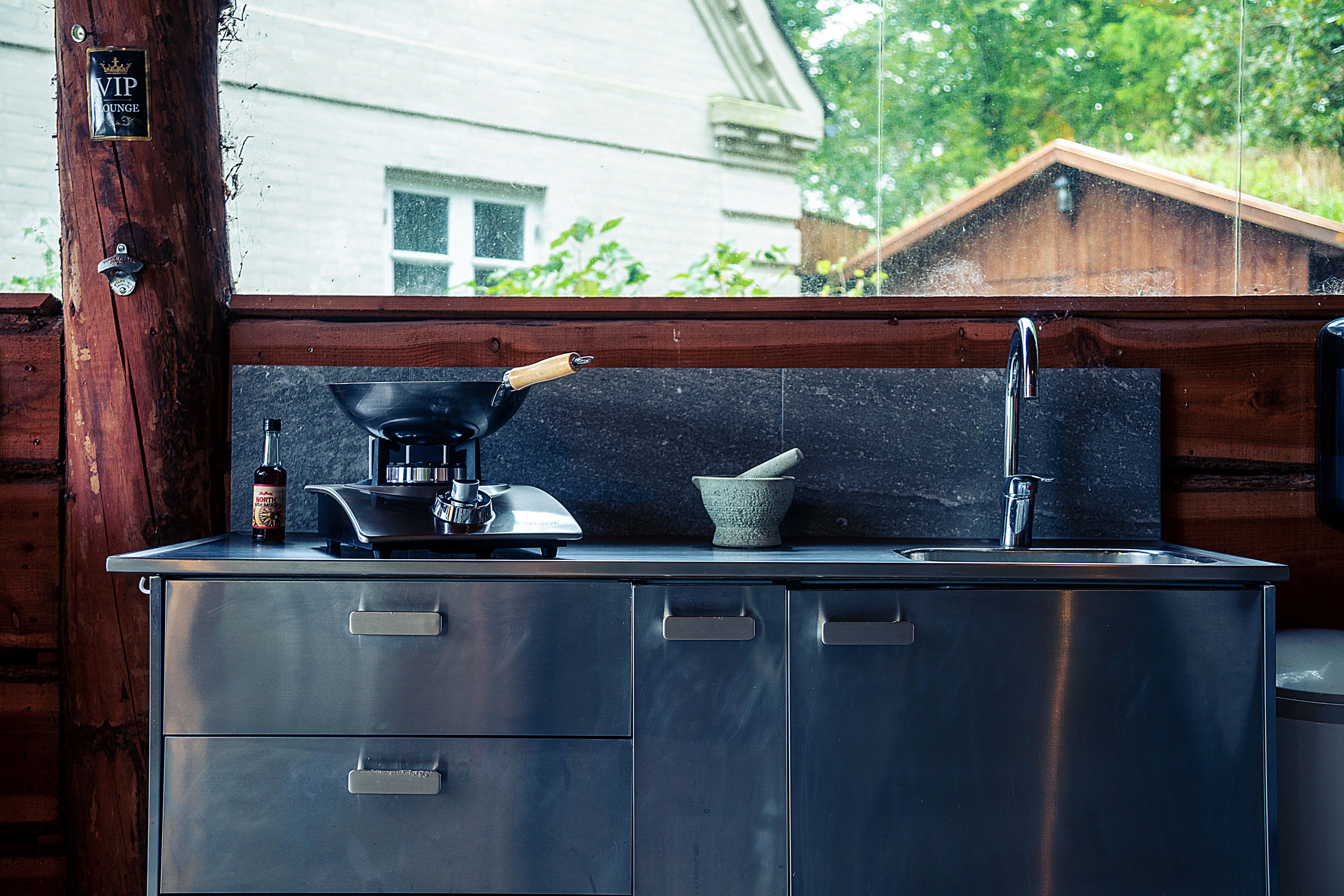 A sustainable outdoor kitchen design featuring eco-friendly materials like recycled concrete and soapstone countertops. The scene includes energy-effi