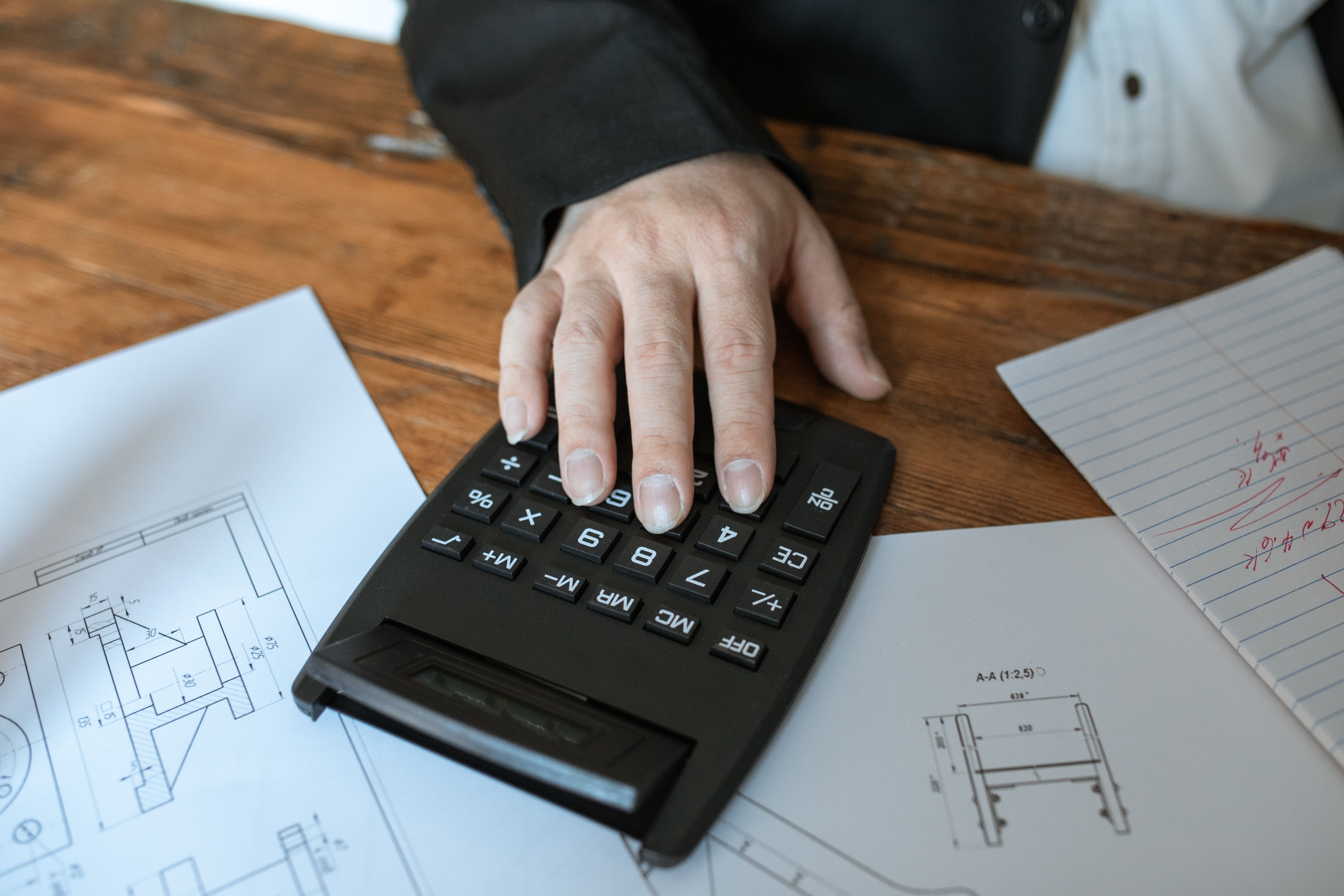 A licensed electrician conducting an electrical load calculation in a neat work environment, with tools and safety gear visible, demonstrating the pla