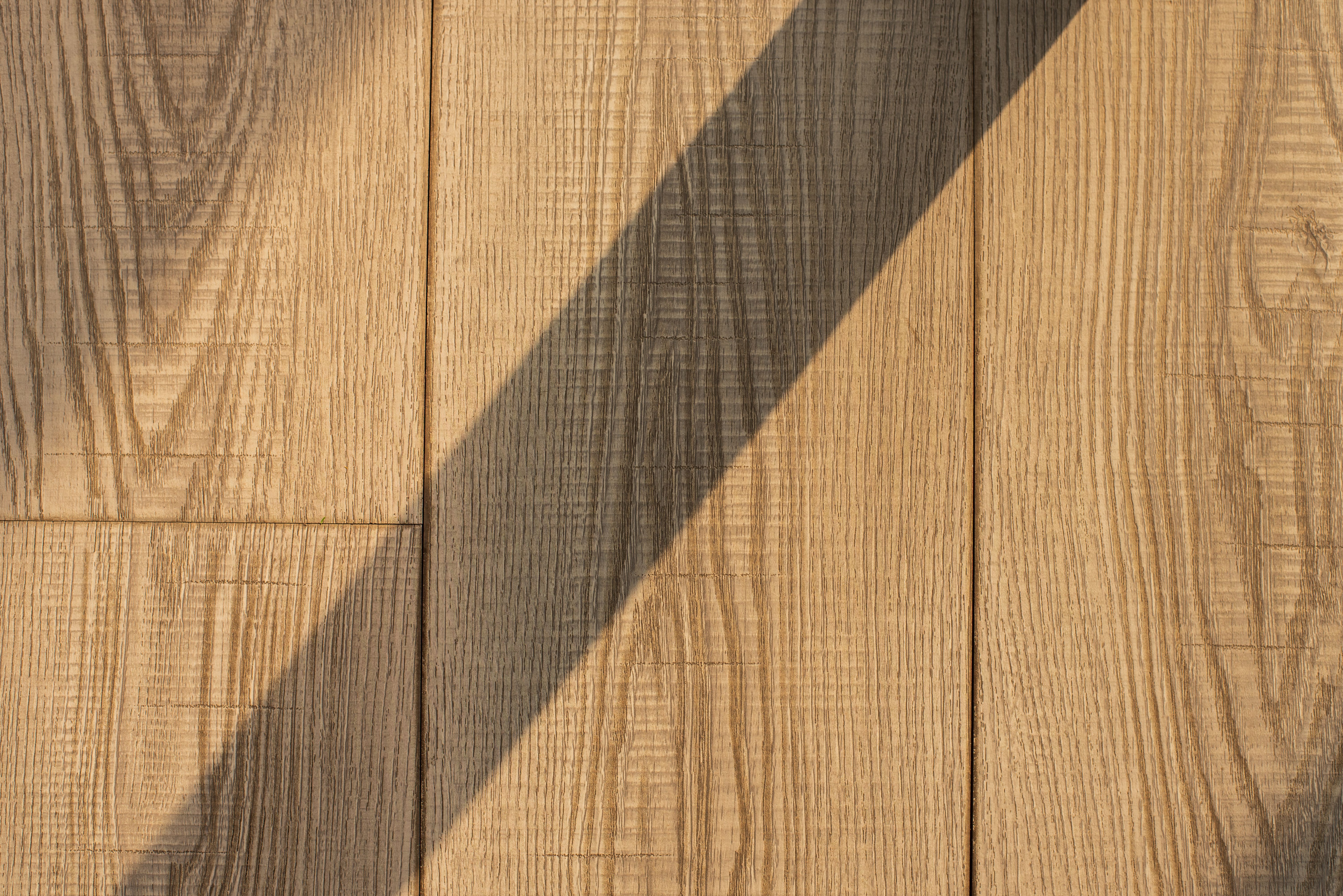 Close-up of a hardwood floor with visible grain patterns, showcasing the natural beauty and variations of wood, with a soft, warm light enhancing the 