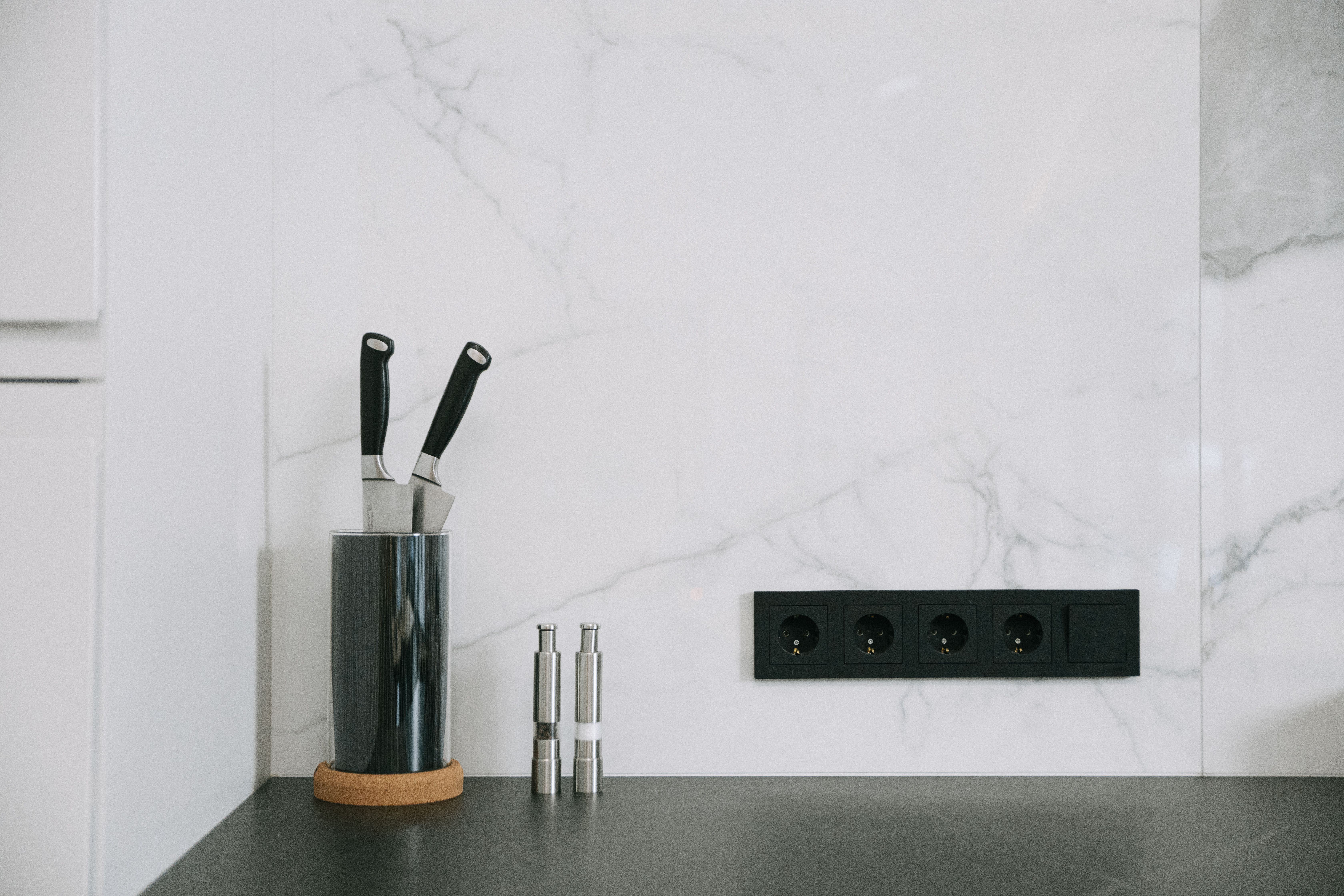 A sleek kitchen featuring metallic backsplash finishes like copper and stainless steel, illustrating the modern and contemporary feel they add to the 