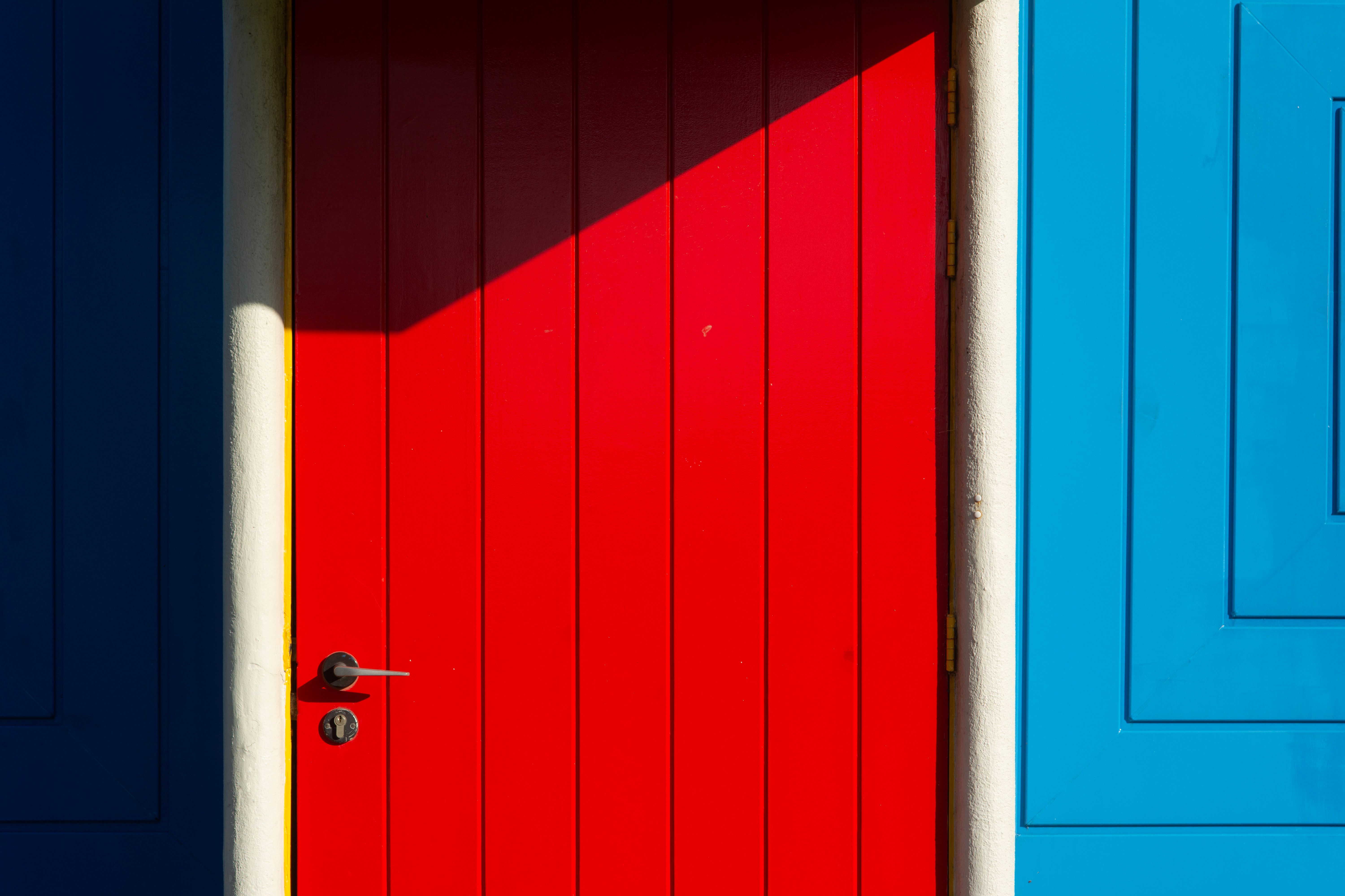 An image of a front door painted in a bold color like teal or mustard yellow, contrasting beautifully with a neutral exterior wall. The setting includ