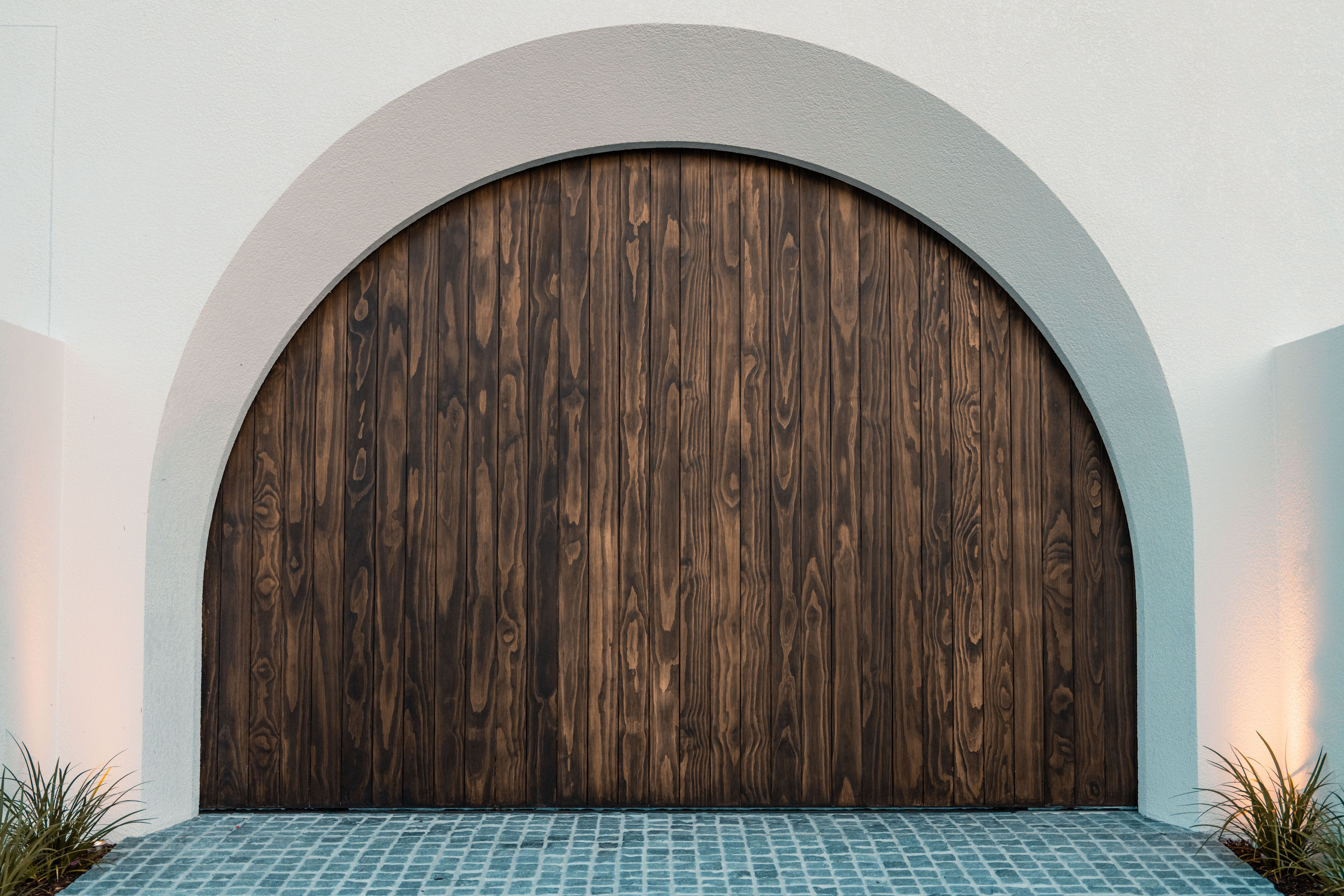 A detailed image of eco-friendly front door materials, such as a door made from reclaimed wood and recycled metal, set against a backdrop of a suburba