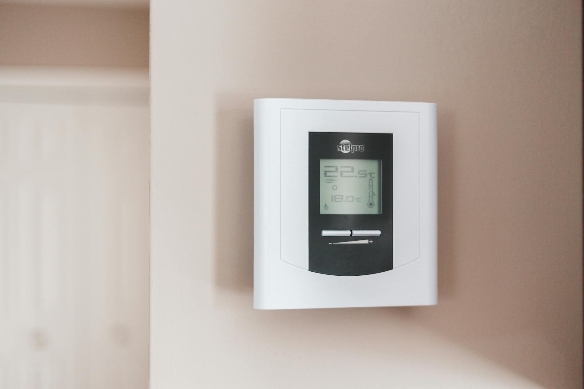 Image of a smart thermostat mounted on a wall in a winter-ready living room, conveying ease of use and modern home comfort.