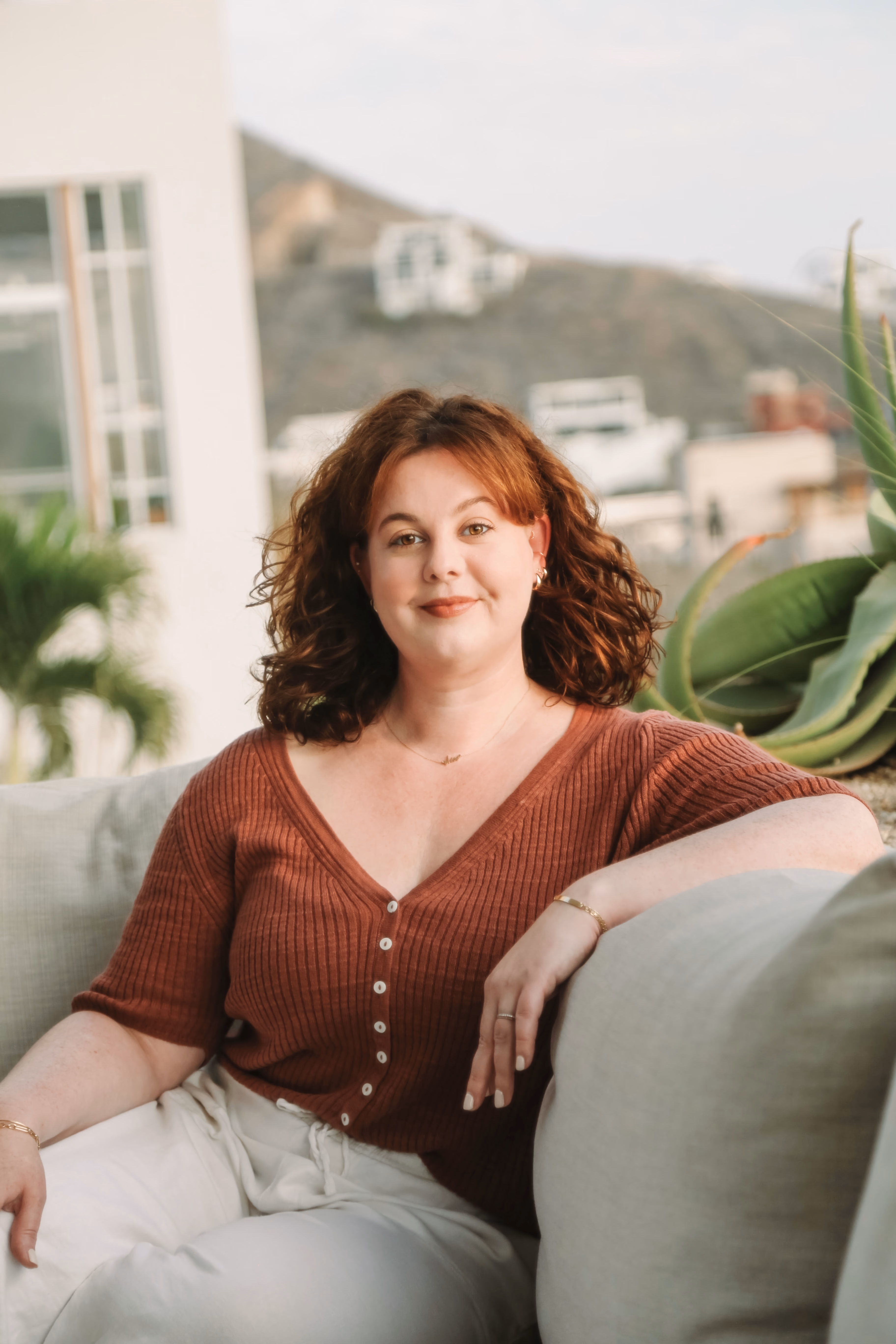 Elise smiling on an outdoor sofa at golden hour