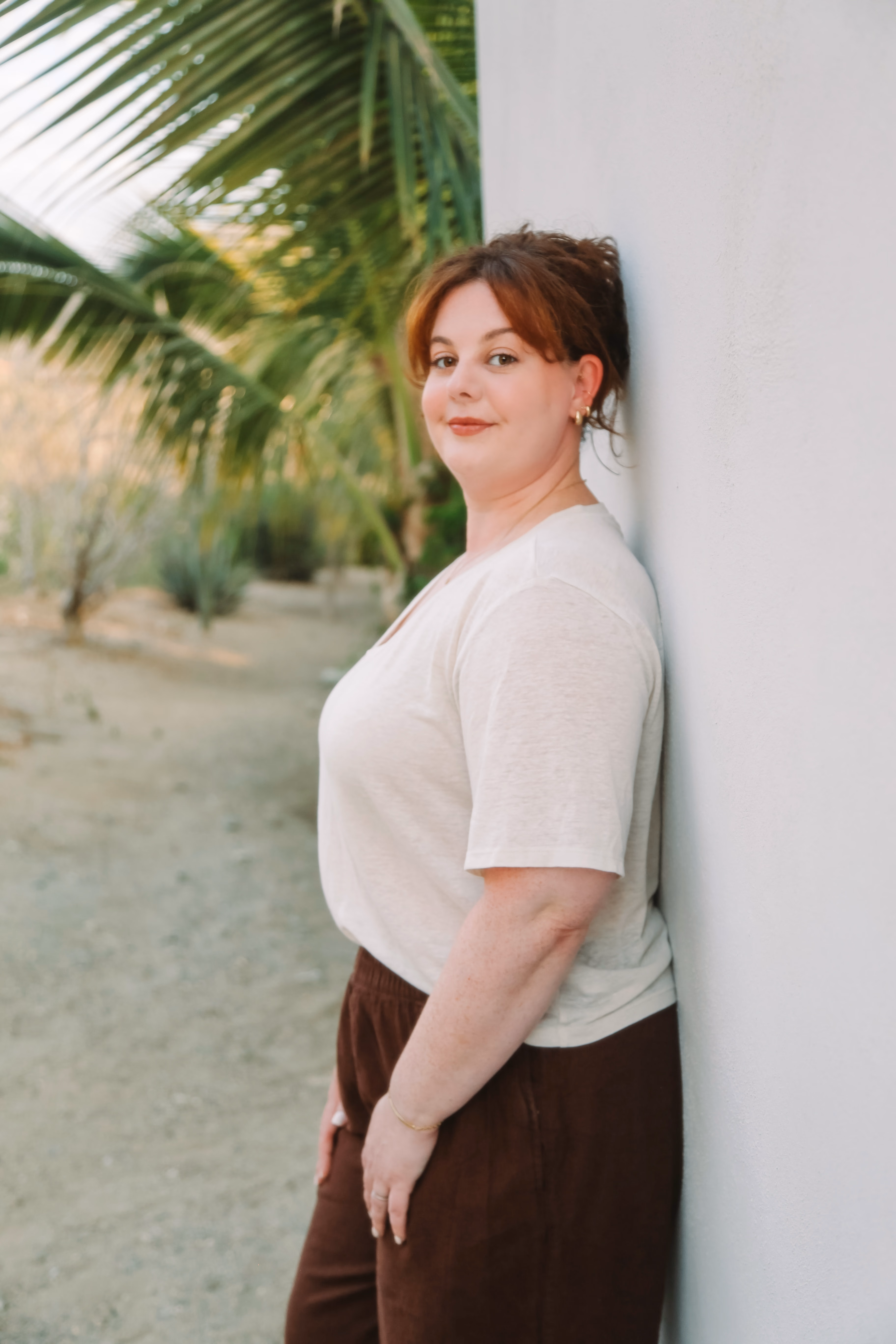 Elise leaning against a white wall in warm afternoon light