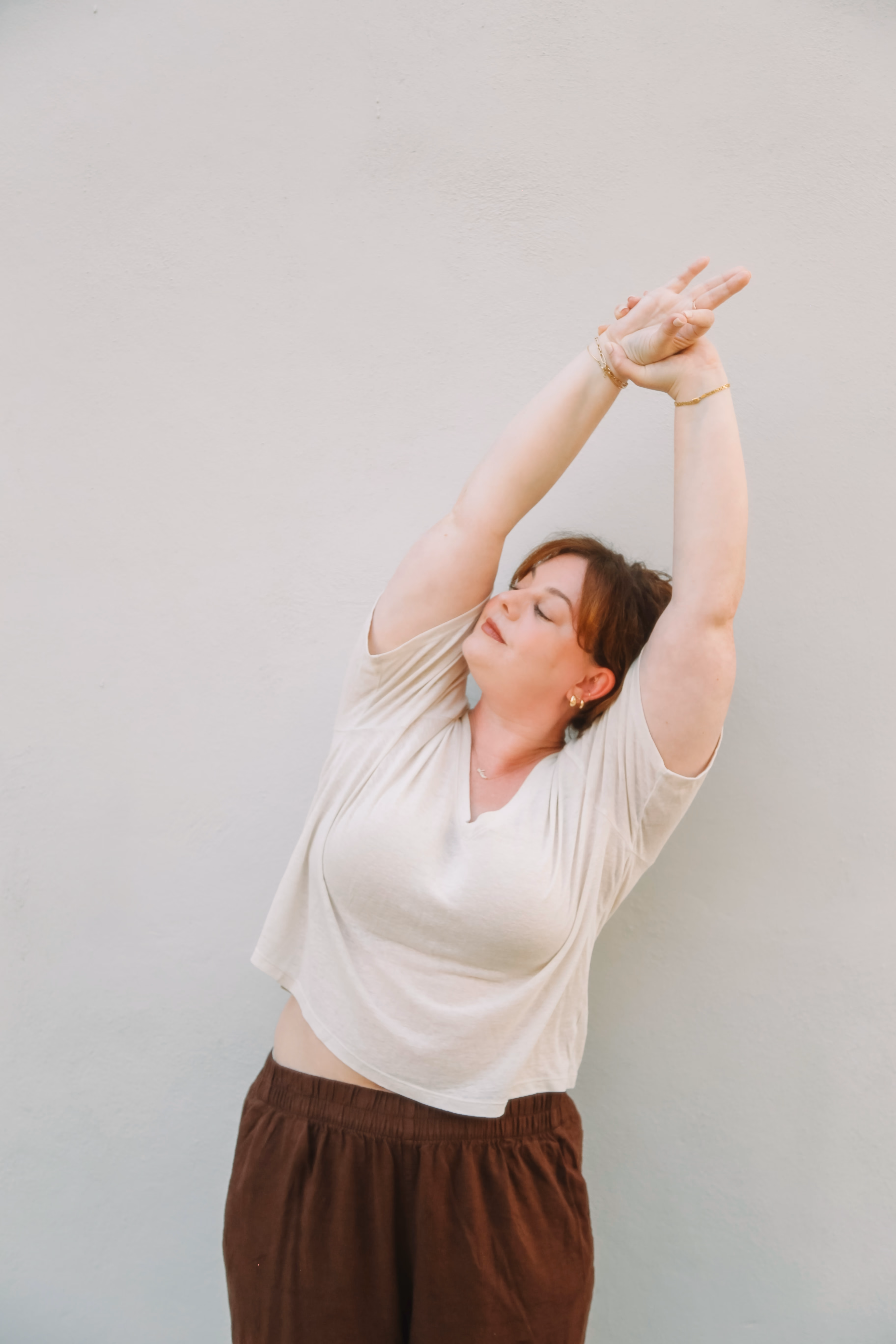 Elise in a standing side stretch with arms raised overhead