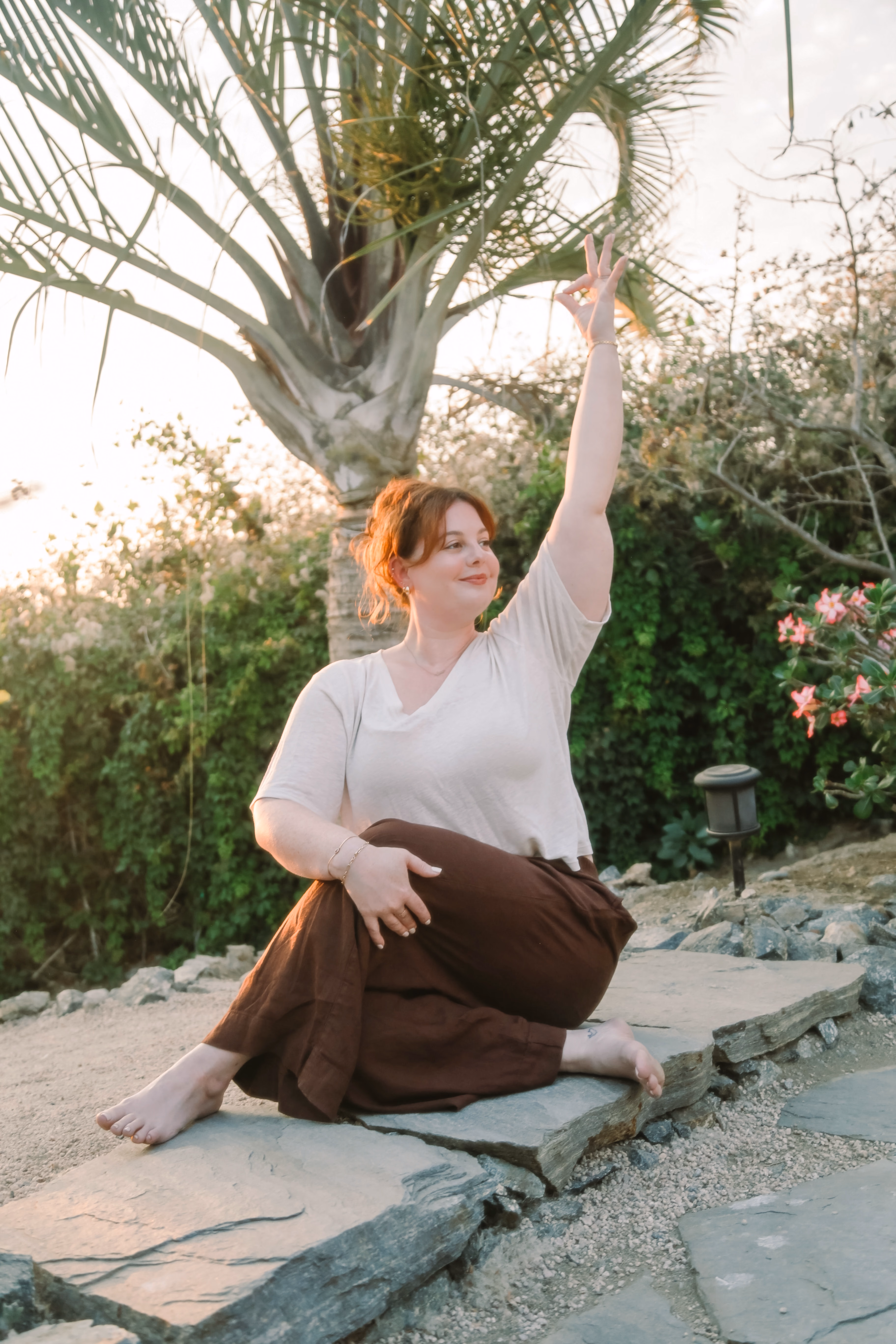 Elise in a seated spinal twist on a stone path in the garden