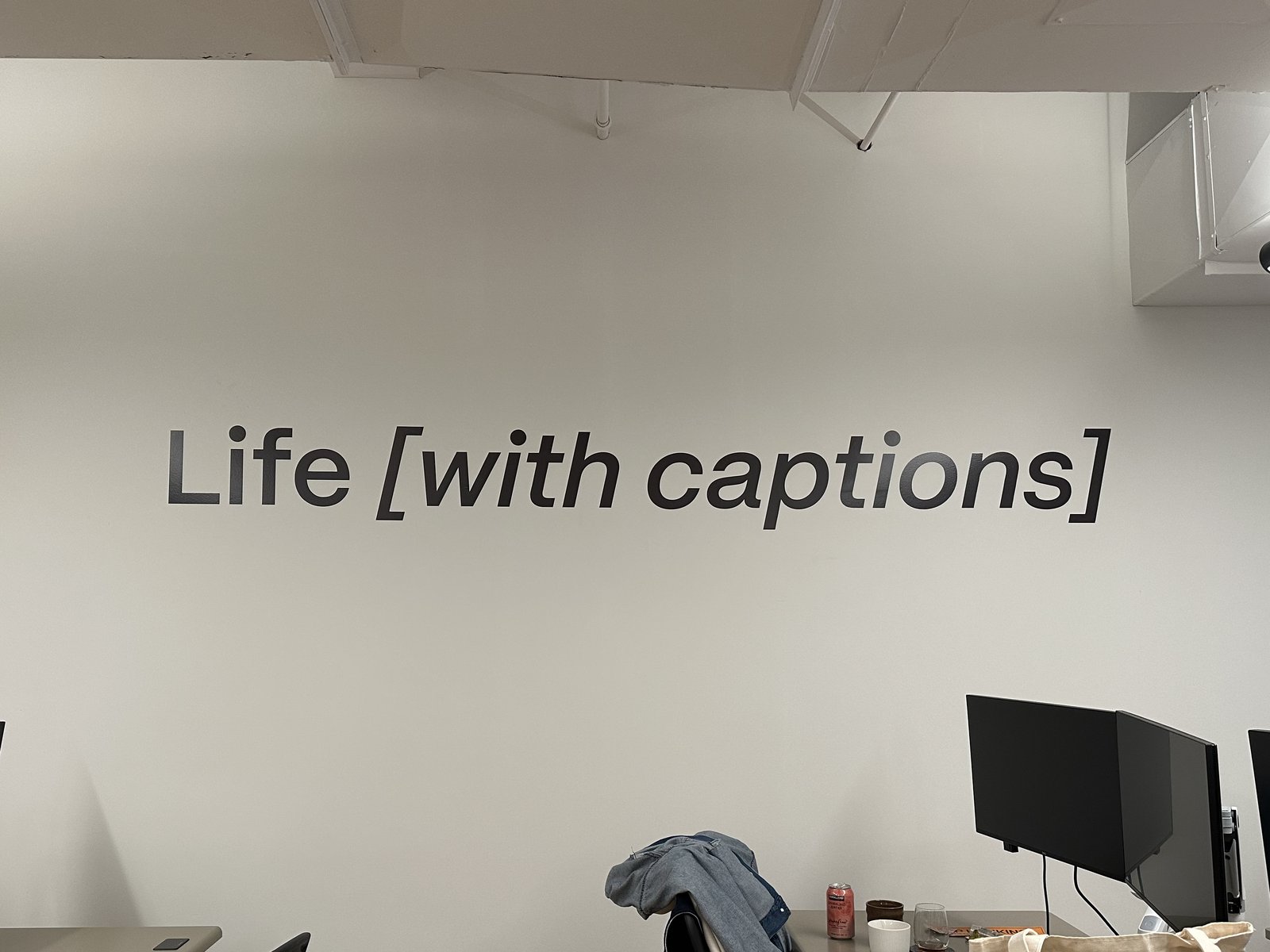 The words "Life [with captions]" on an office wall