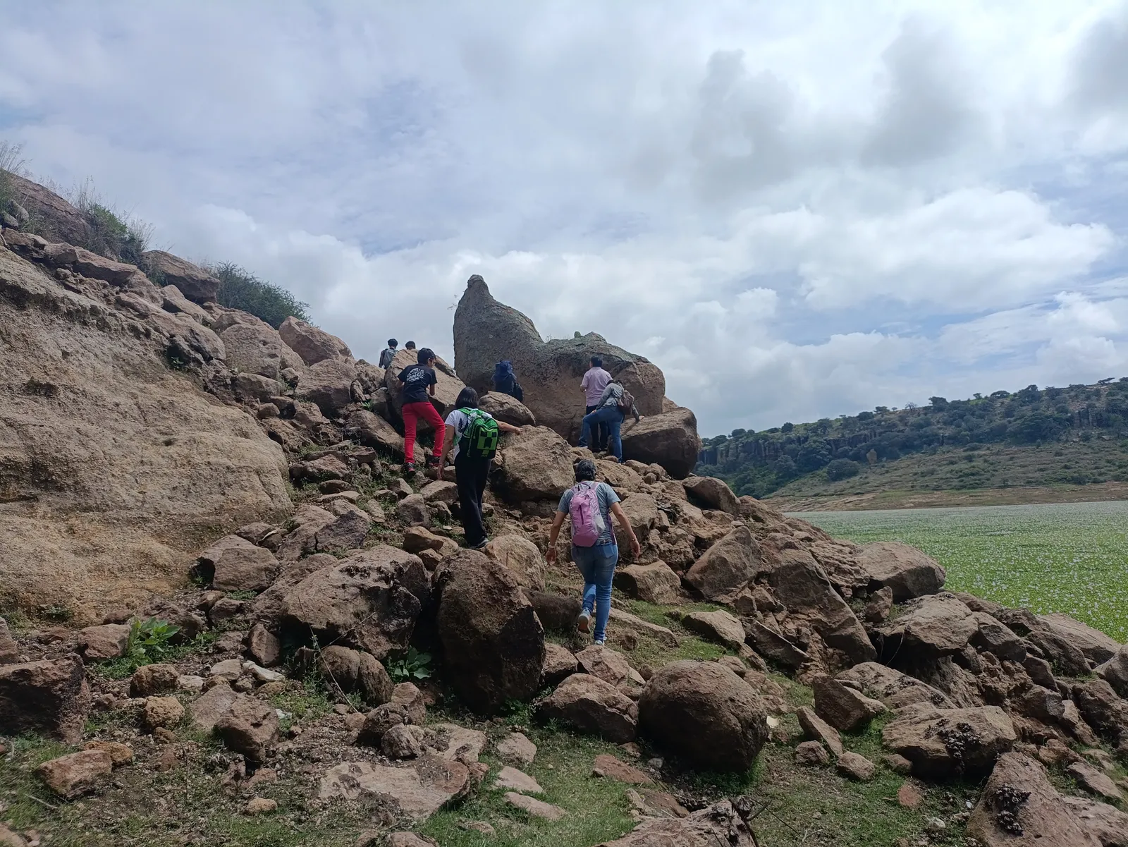 Senderistas ascendiendo entre formaciones rocosas junto a la presa de Picos de Yospi, Amealco.