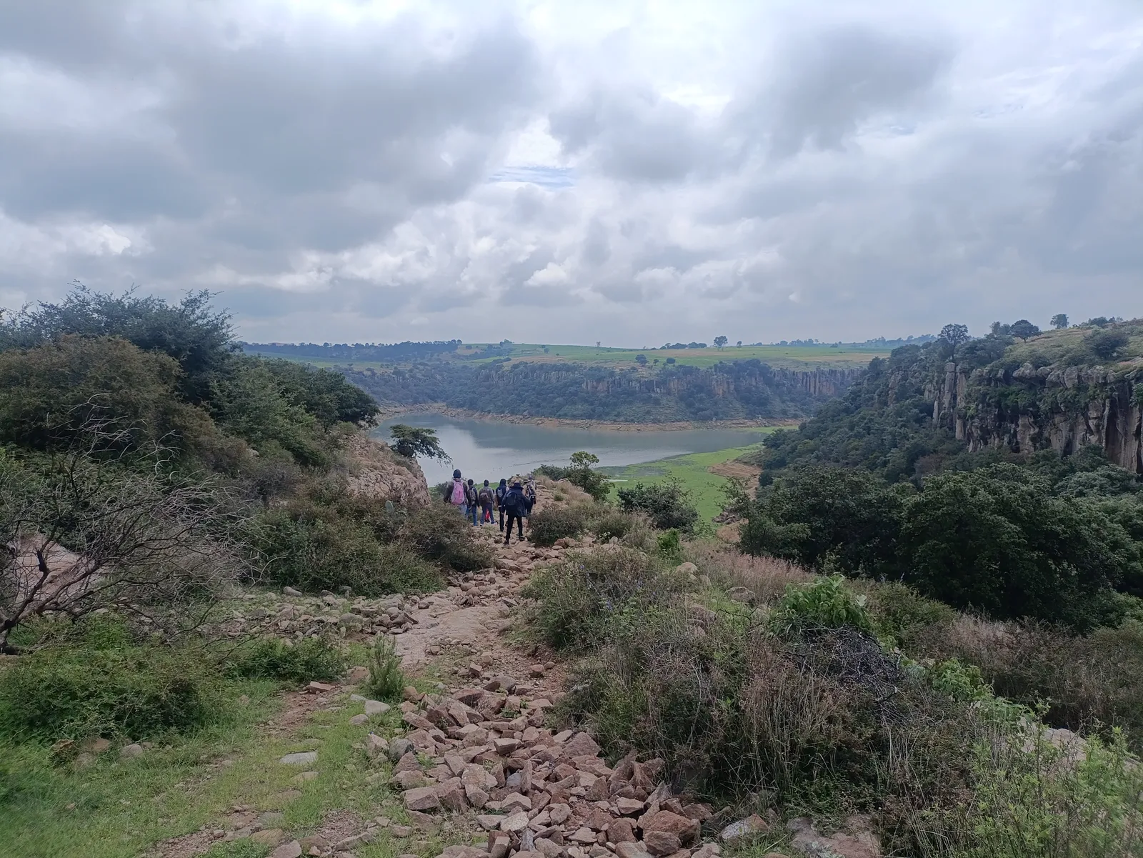 Grupo de senderistas descendiendo por el sendero rocoso hacia la presa de Picos de Yospi, Amealco.